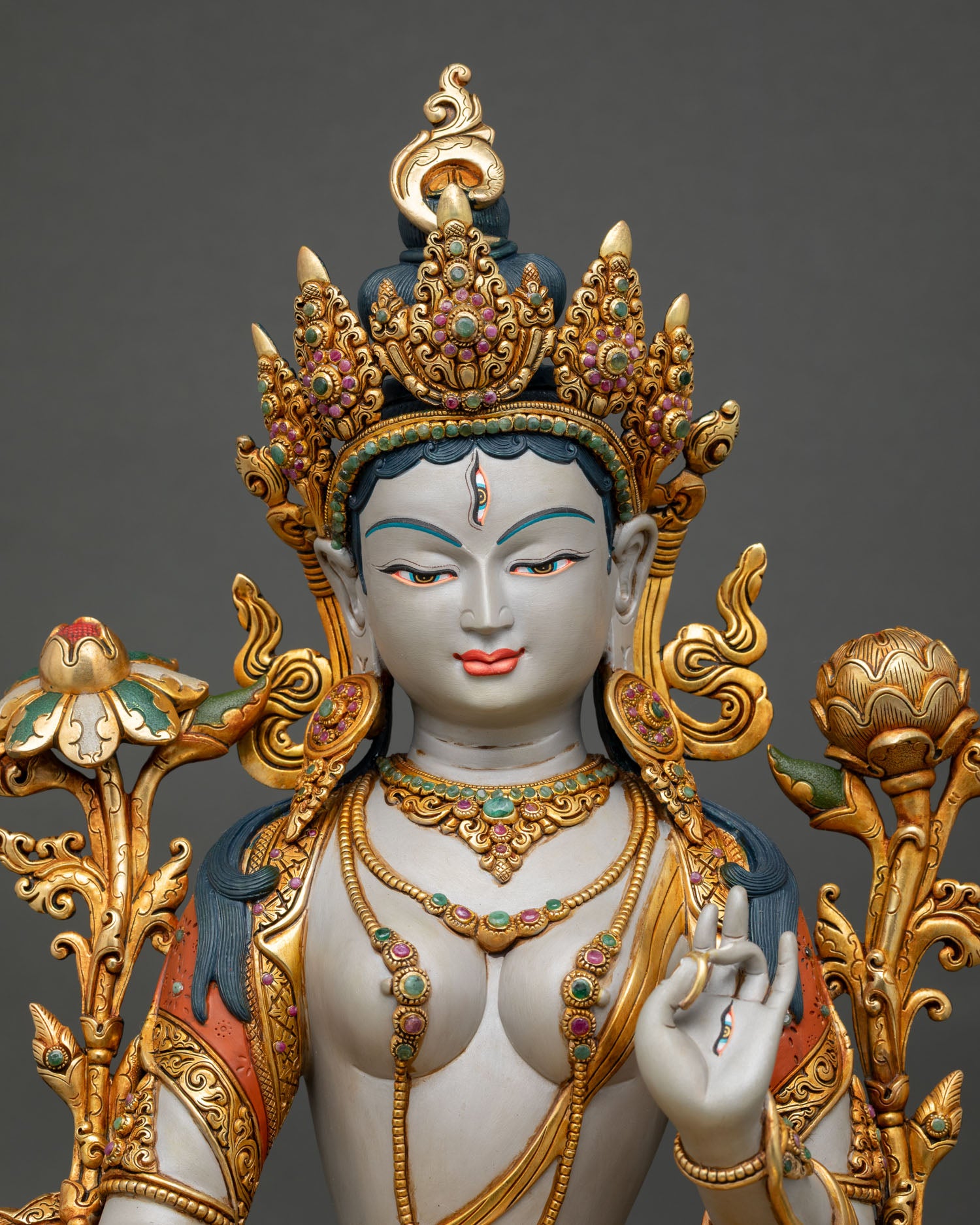 close up view of white tara statue showing gold gilded details and ornaments