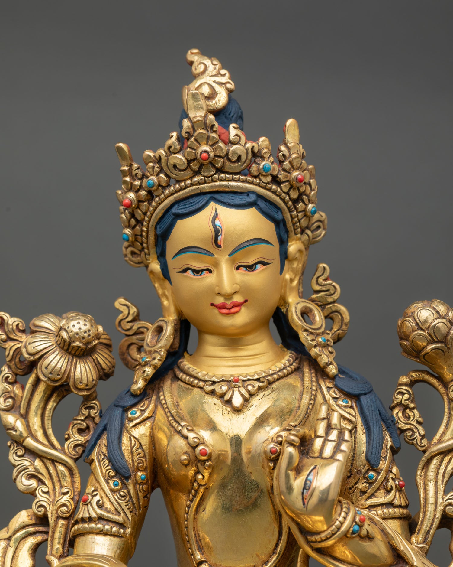 Close up view of White Tara statue showing gold painted face, seven eyes detail, and semi precious stone inlays with Himalayan Newari craftsmanship