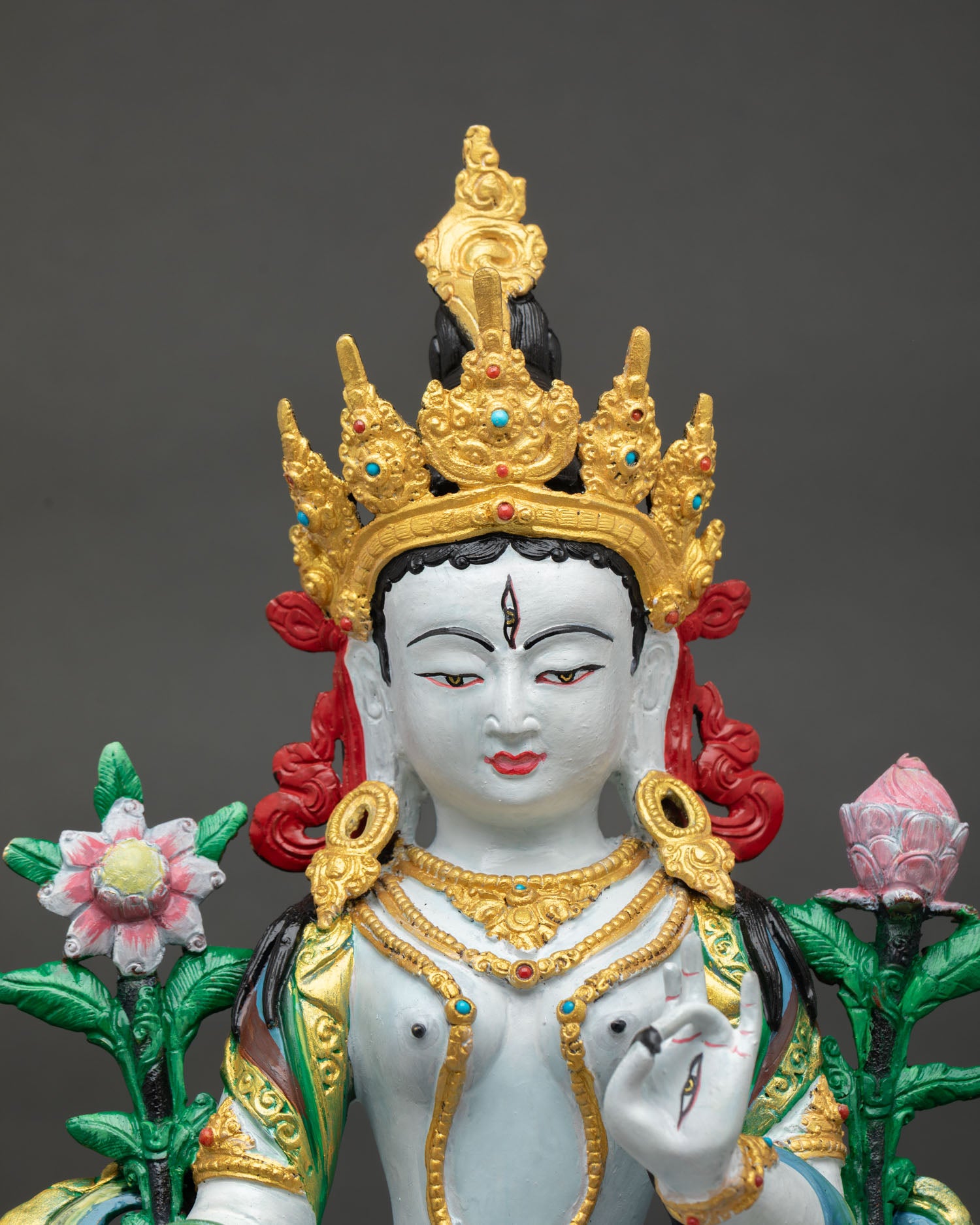 Close-up view of White Tara statue showing serene face, gold-accented crown, and finely painted sacred features.