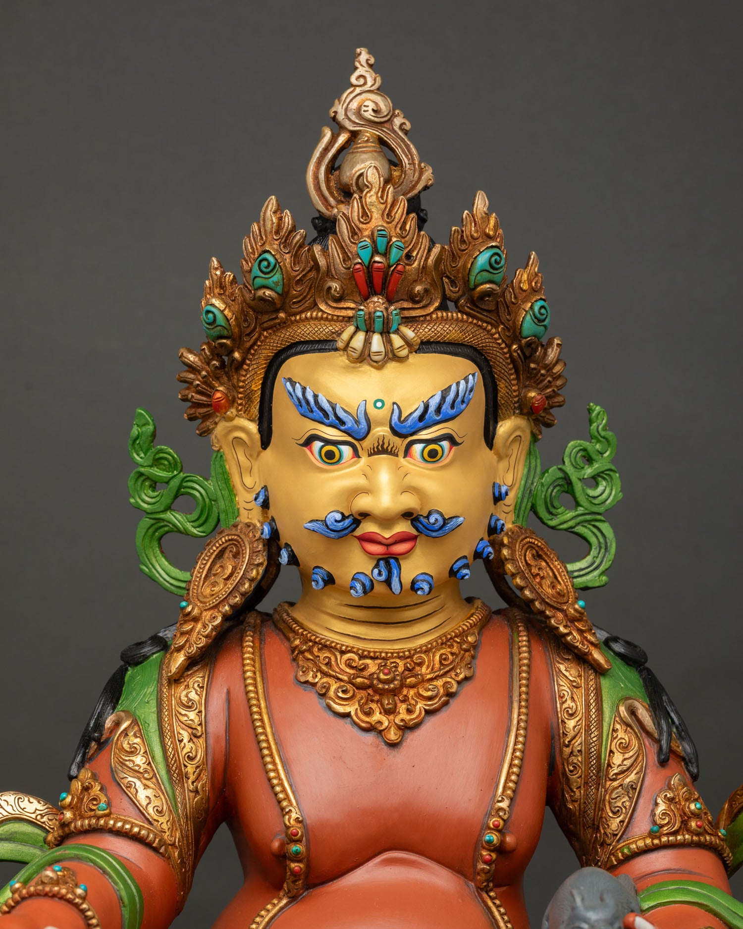 close up view of yellow dzambhala statue showing intricate gold details and sacred ornaments