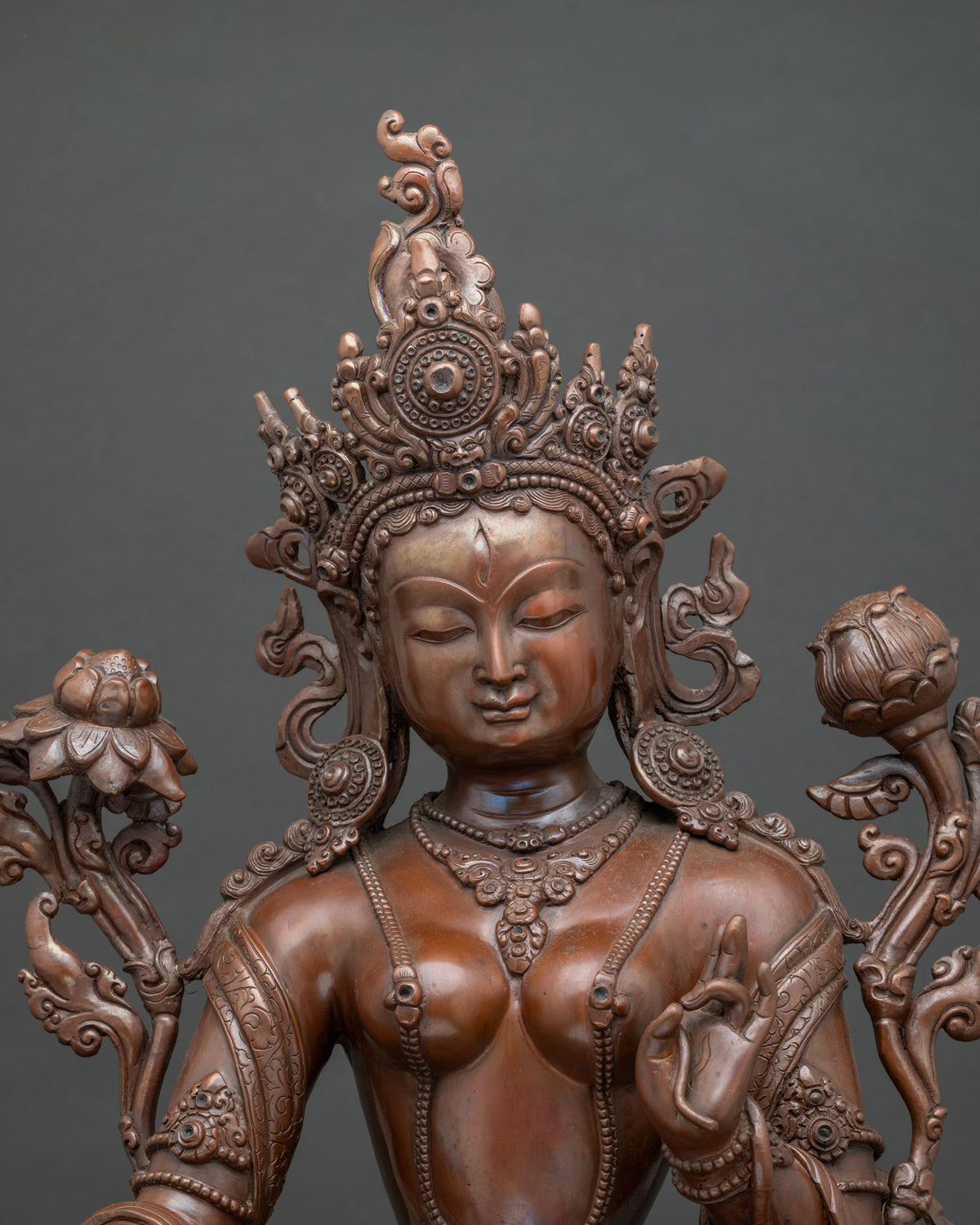 Close up White Tara statue showing serene face seven eyes and intricate copper details.