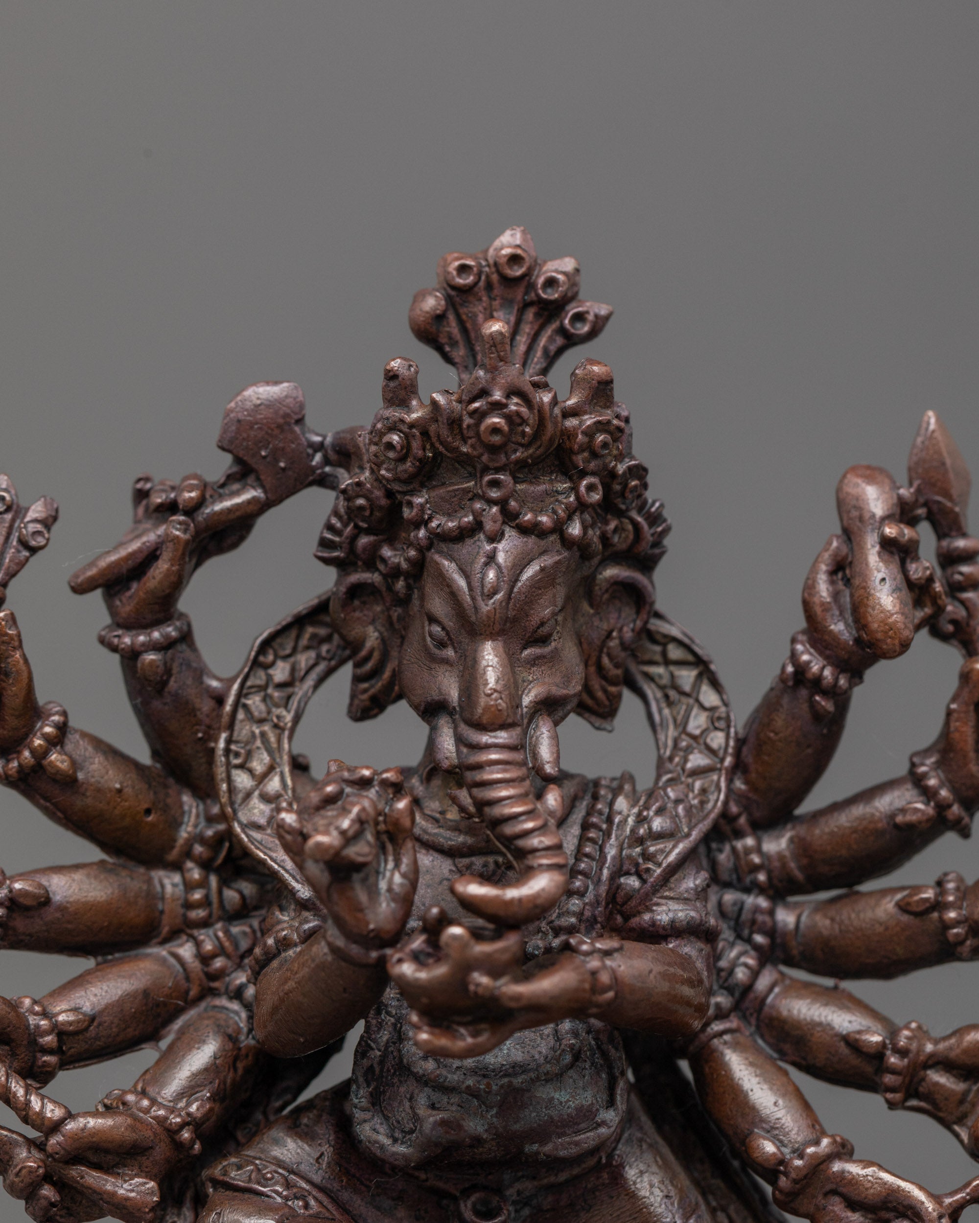 close-up of oxidized copper Ganesha face with halo and intricate sacred object details