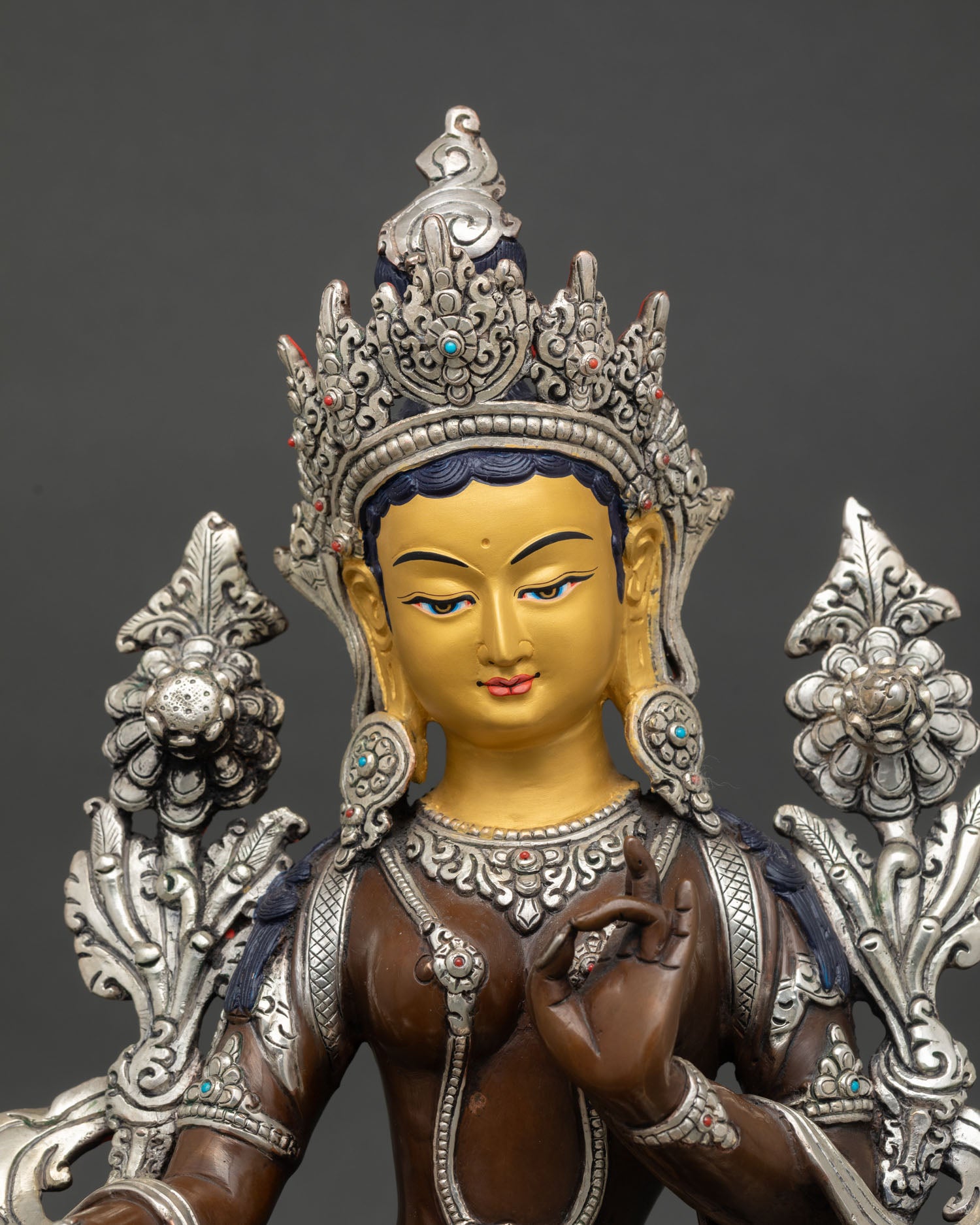 Close view of Green Tara face showing gold painted details, intricate Himalayan craftsmanship, and compassionate expression.