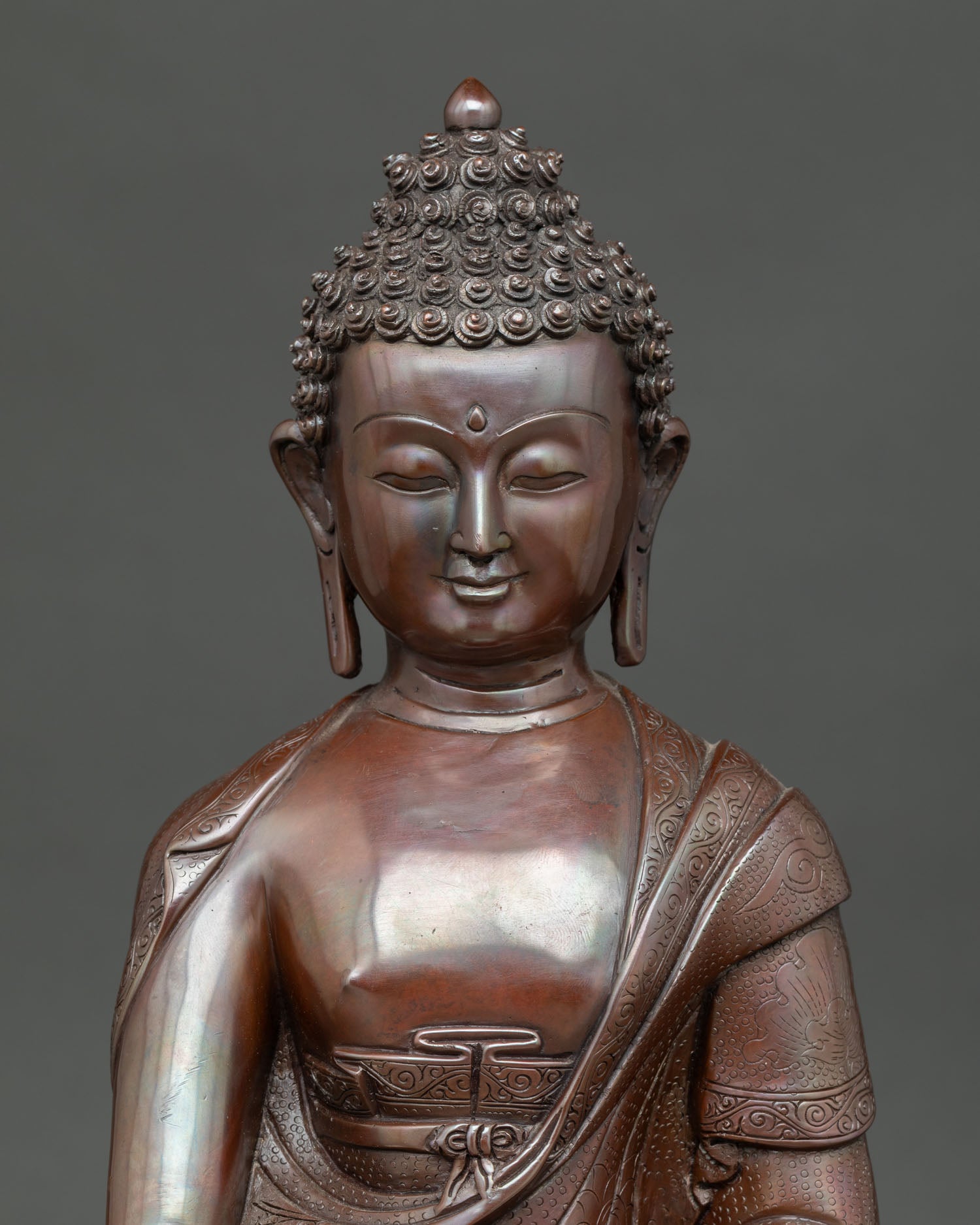 Close view of Shakyamuni Buddha statue showing serene expression, oxidized copper texture, and Nepalese craftsmanship.