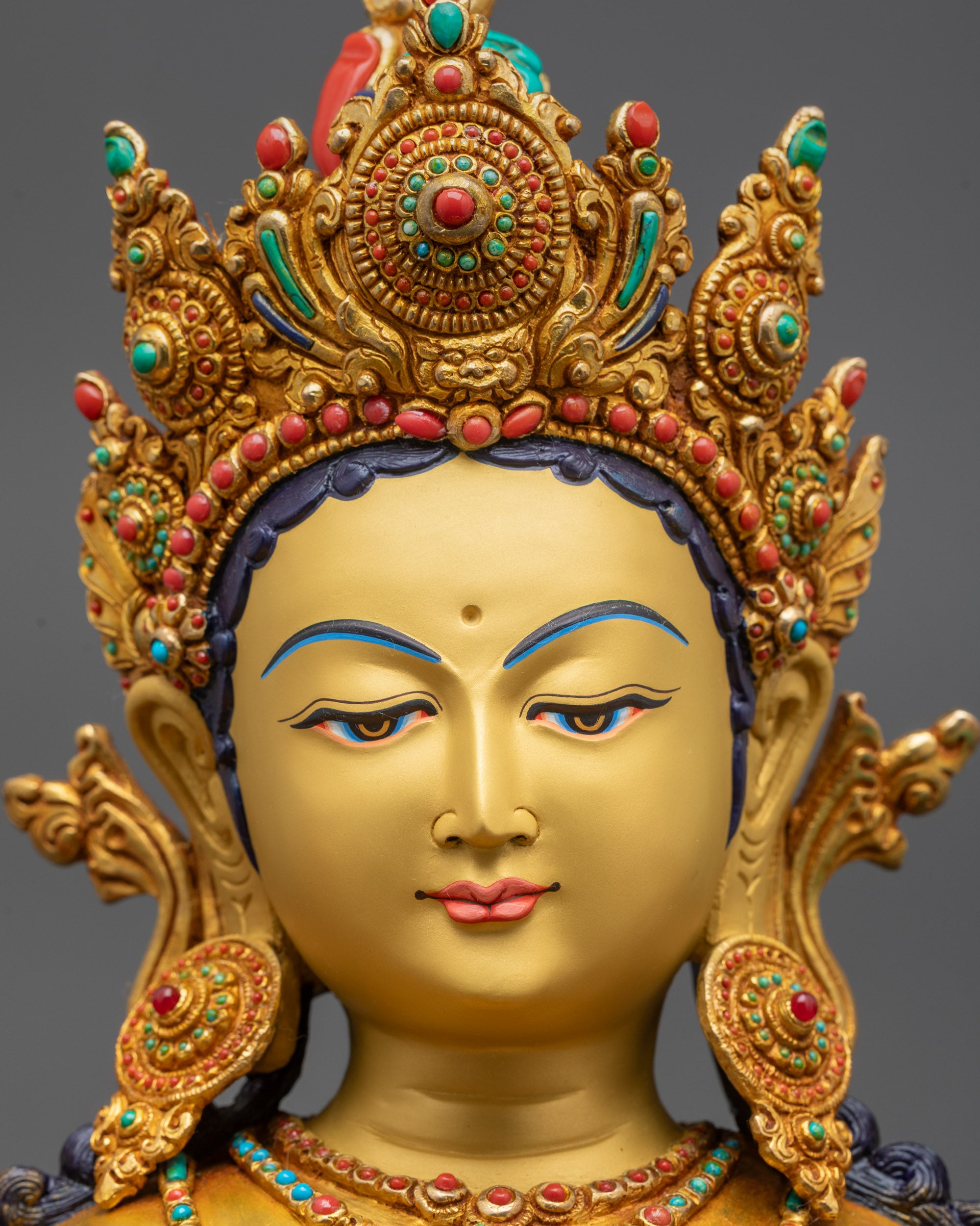 close up Green Tara gold gilded face with jeweled crown, utpala flower and ornaments