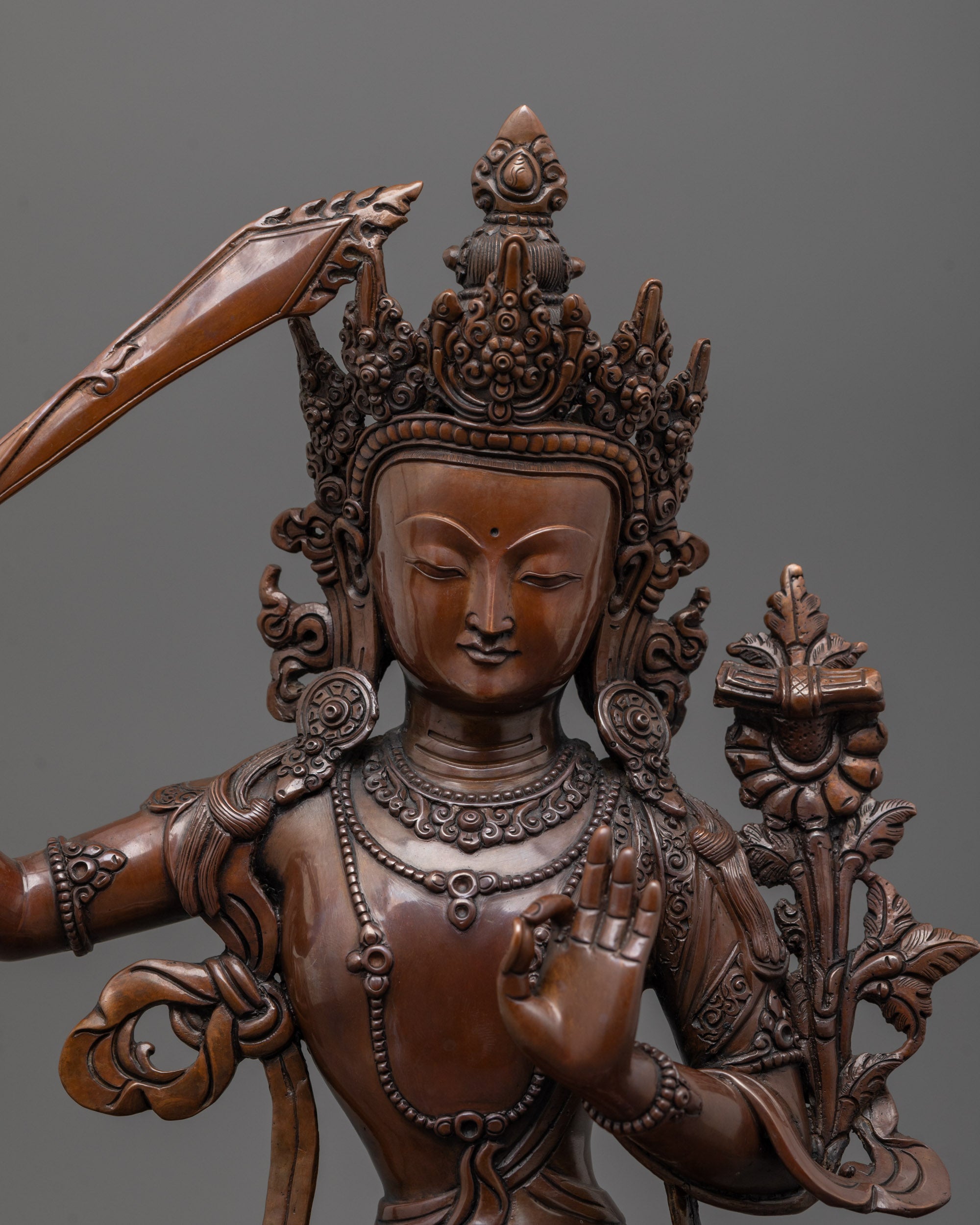 close up of Manjushri statue showing oxidized copper face and intricate wax-carved details