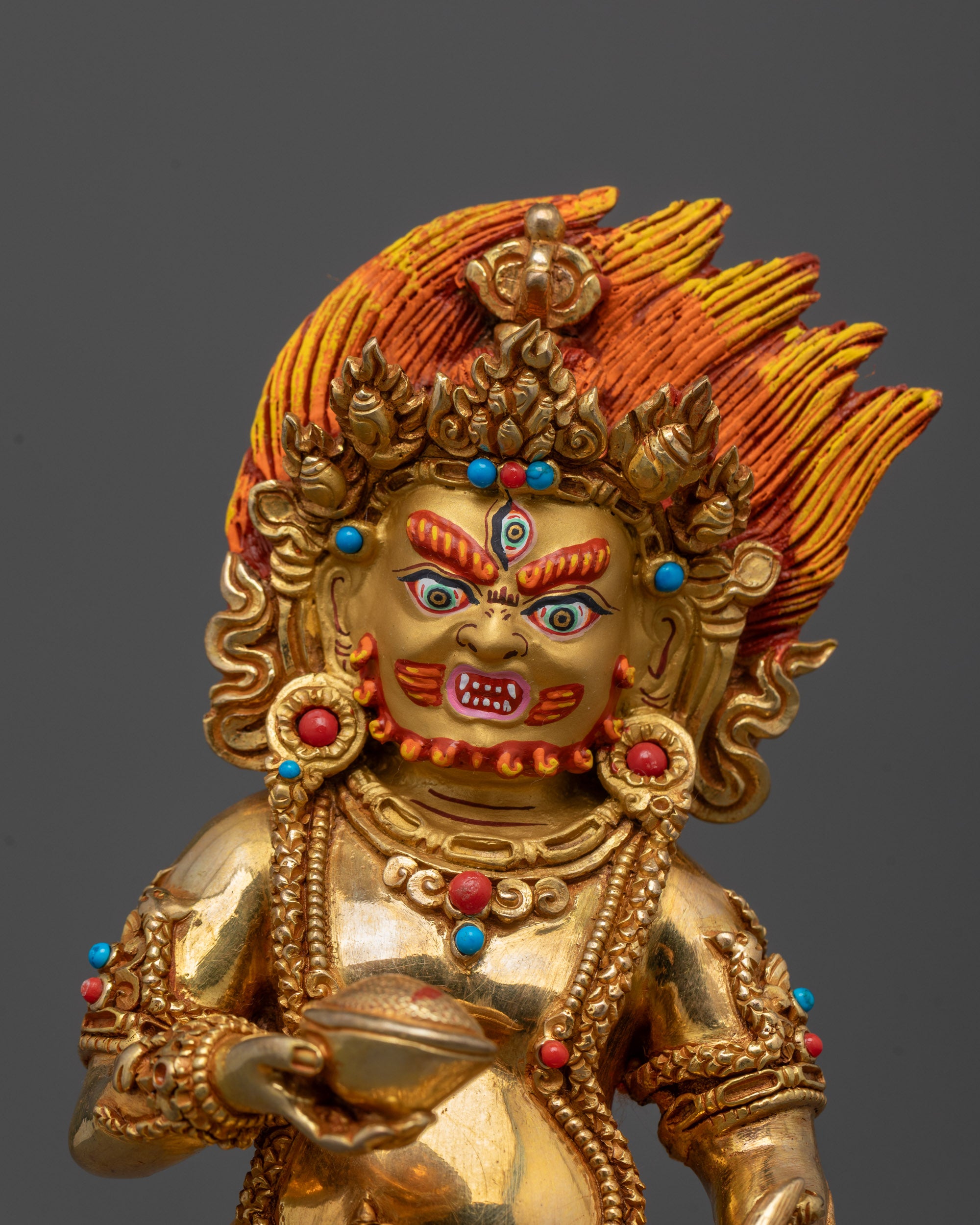 close up of black dzambhala face showing third eye and fierce expression with semi-precious stones