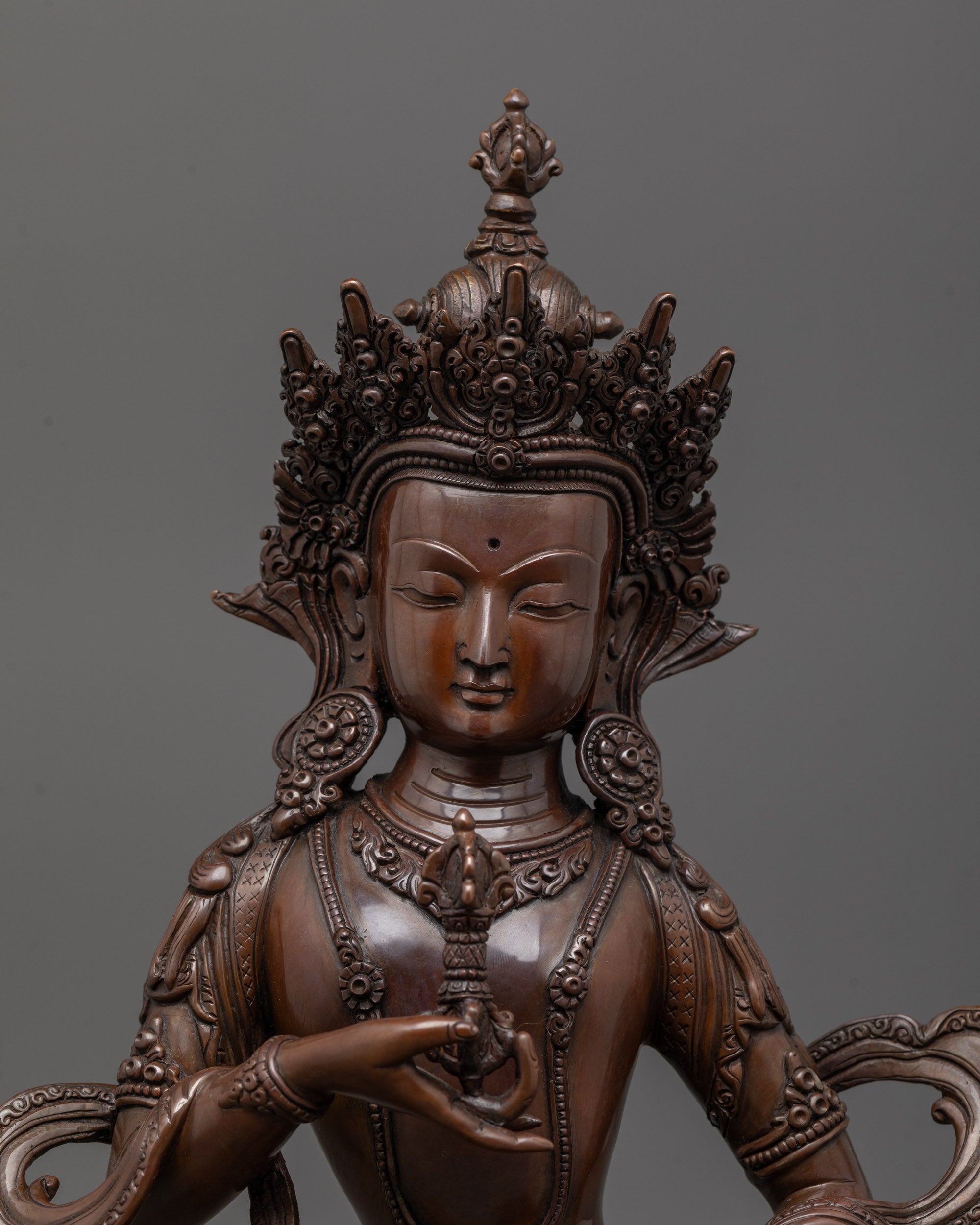 close up of dorje sempa face and vajra bell details in oxidized copper sculpture