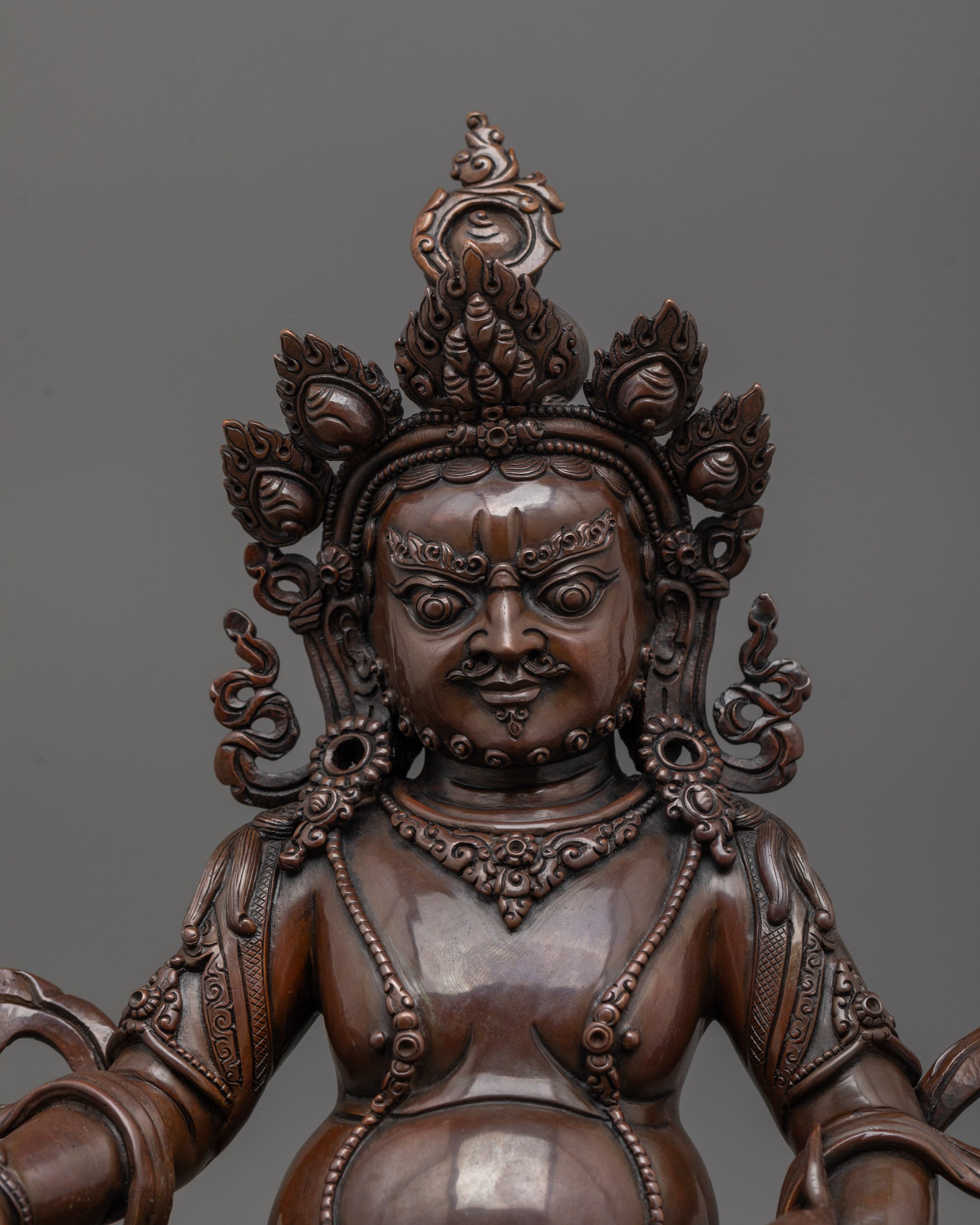 close up of dzambhala statue highlighting jewel-spitting mongoose and intricate facial features