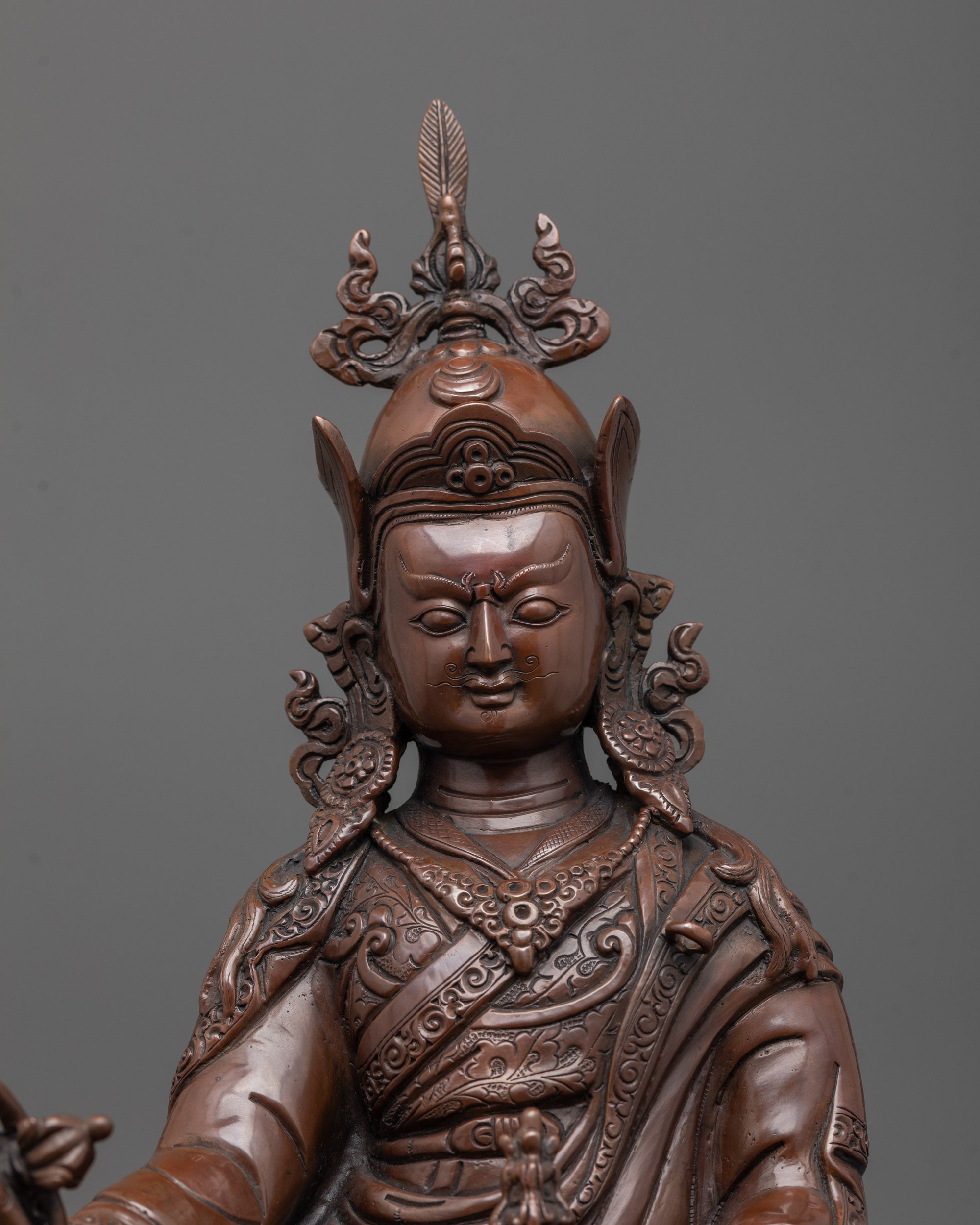 close up of guru rinpoche statue showing trident vajra and serene facial expression
