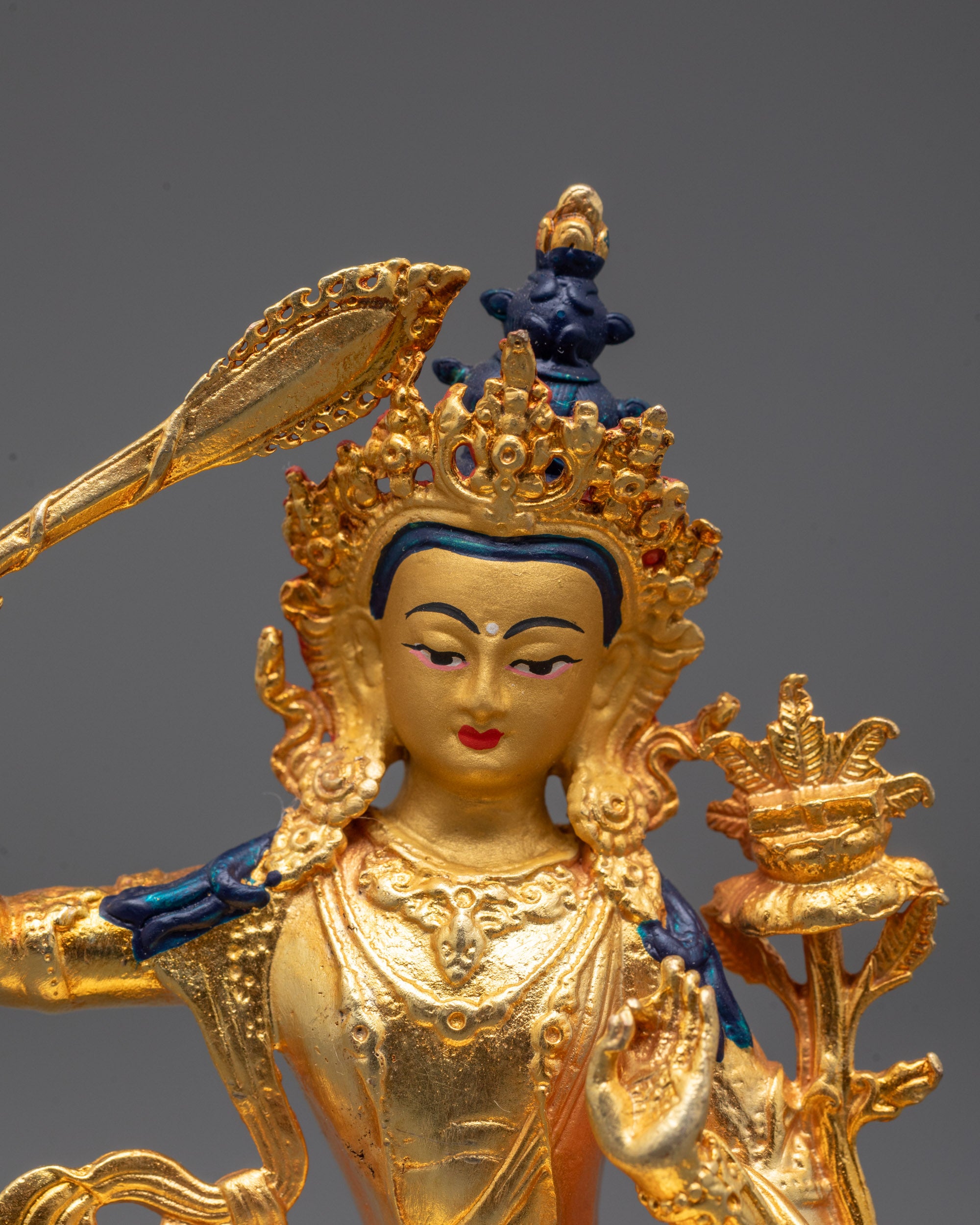 close up of manjushri statue's gold-gilded face and precision-carved jewelry details