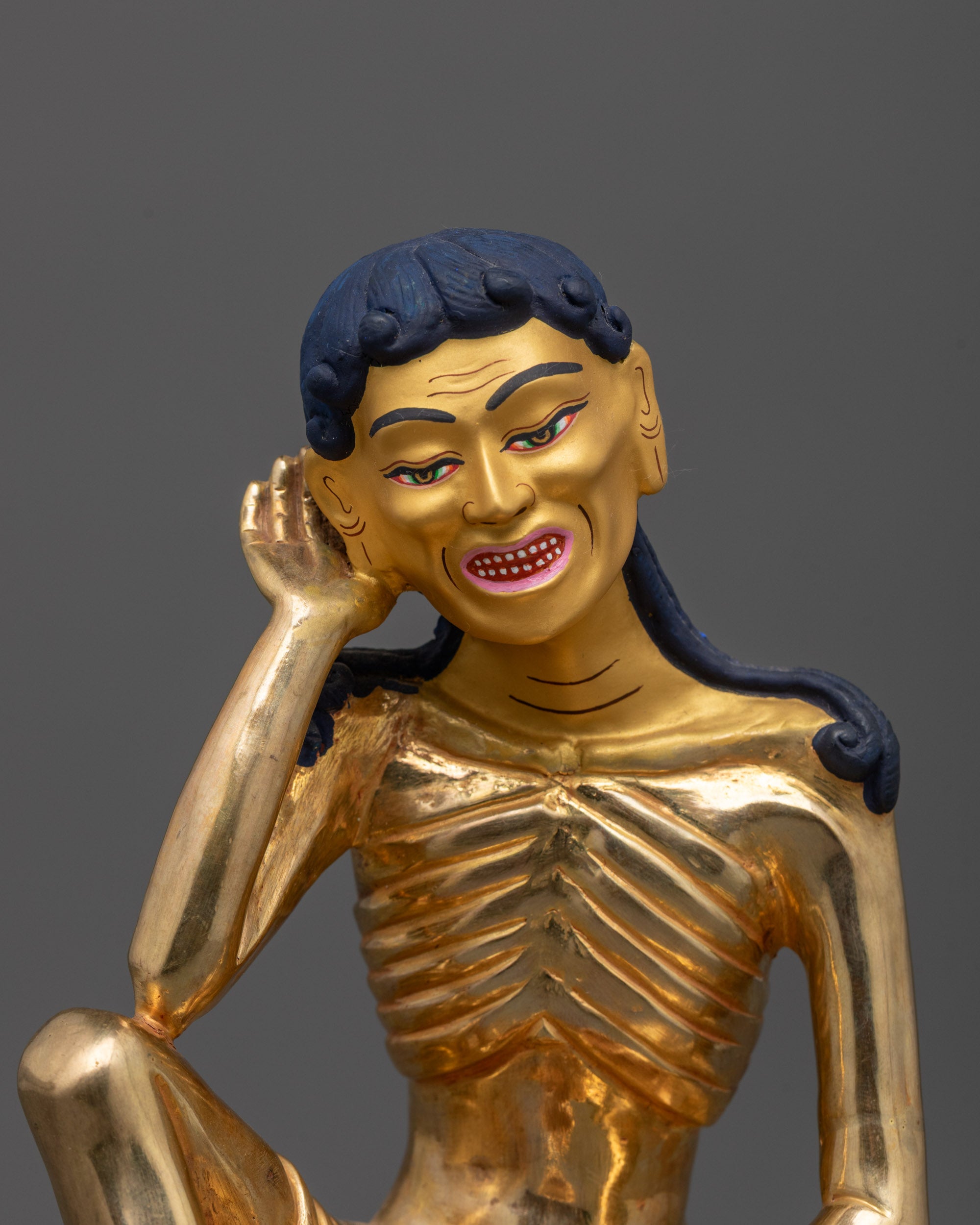 close up of milarepa statue showing hand near ear and kapala detail