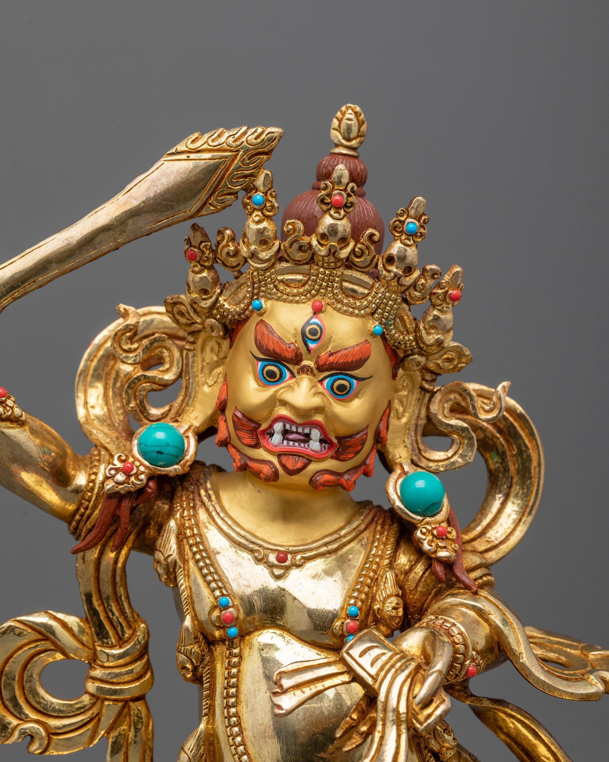 close up of wrathful manjushri face with 24k gold gilding and fierce piercing gaze