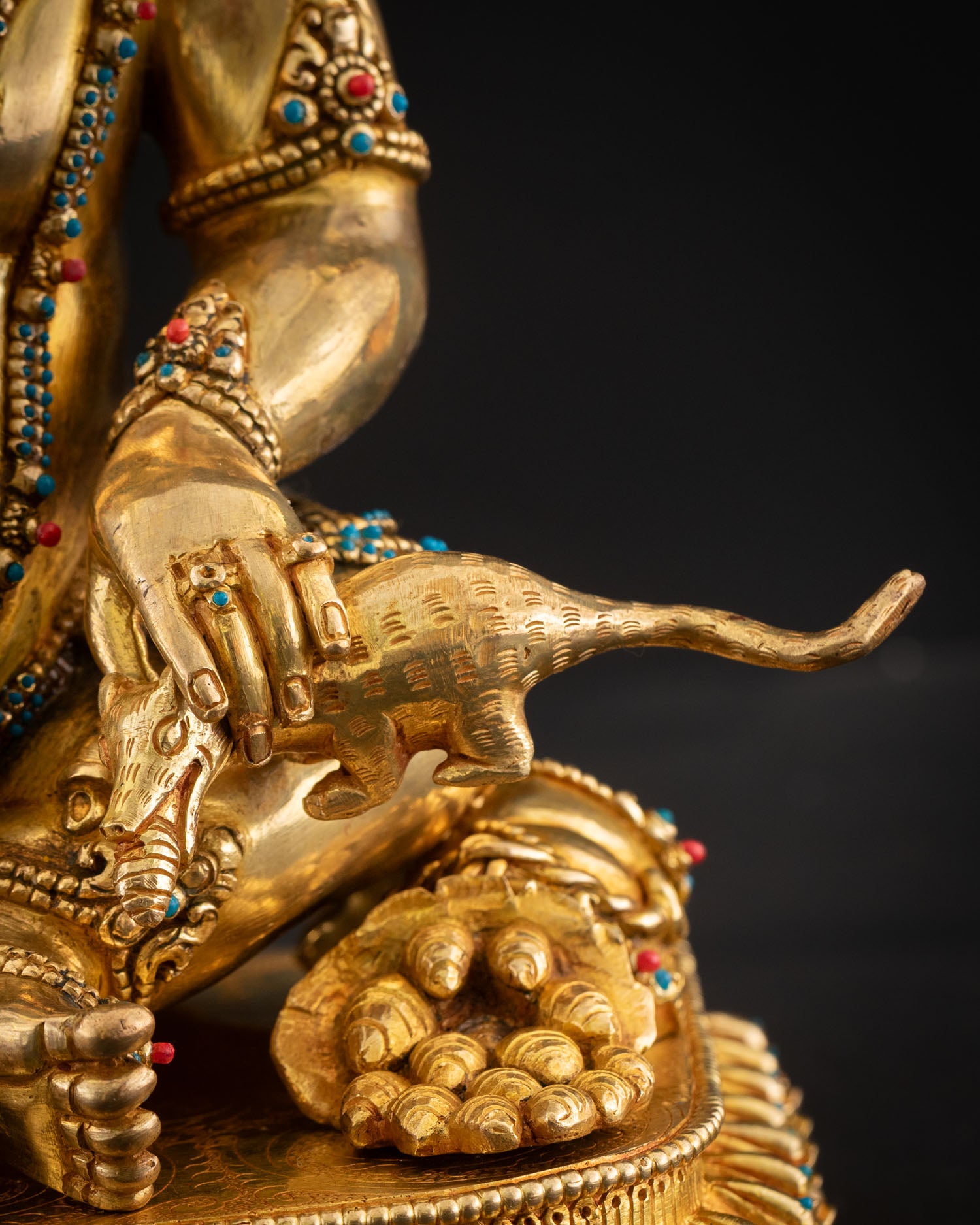 Detail hand holding mongoose, Dzambhala statue wealth prosperity symbolism Nepal