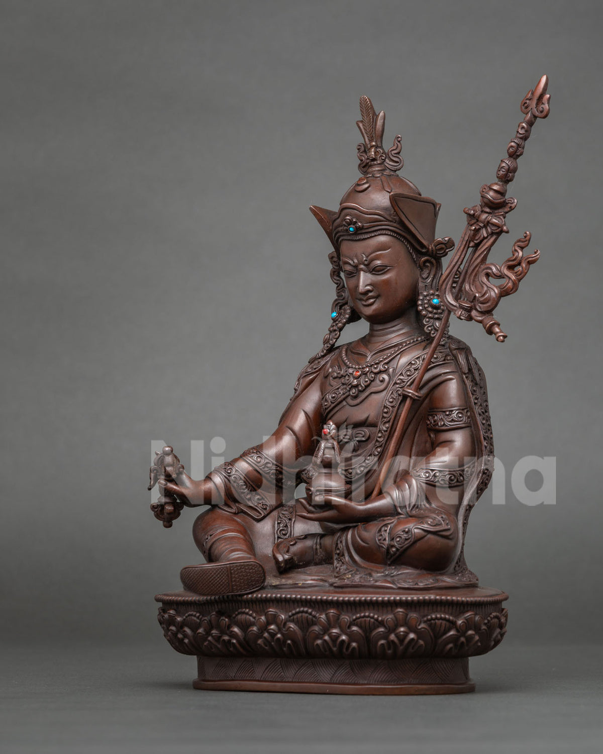 Detail of skull cup in lap of Guru Rinpoche copper statue on lotus base