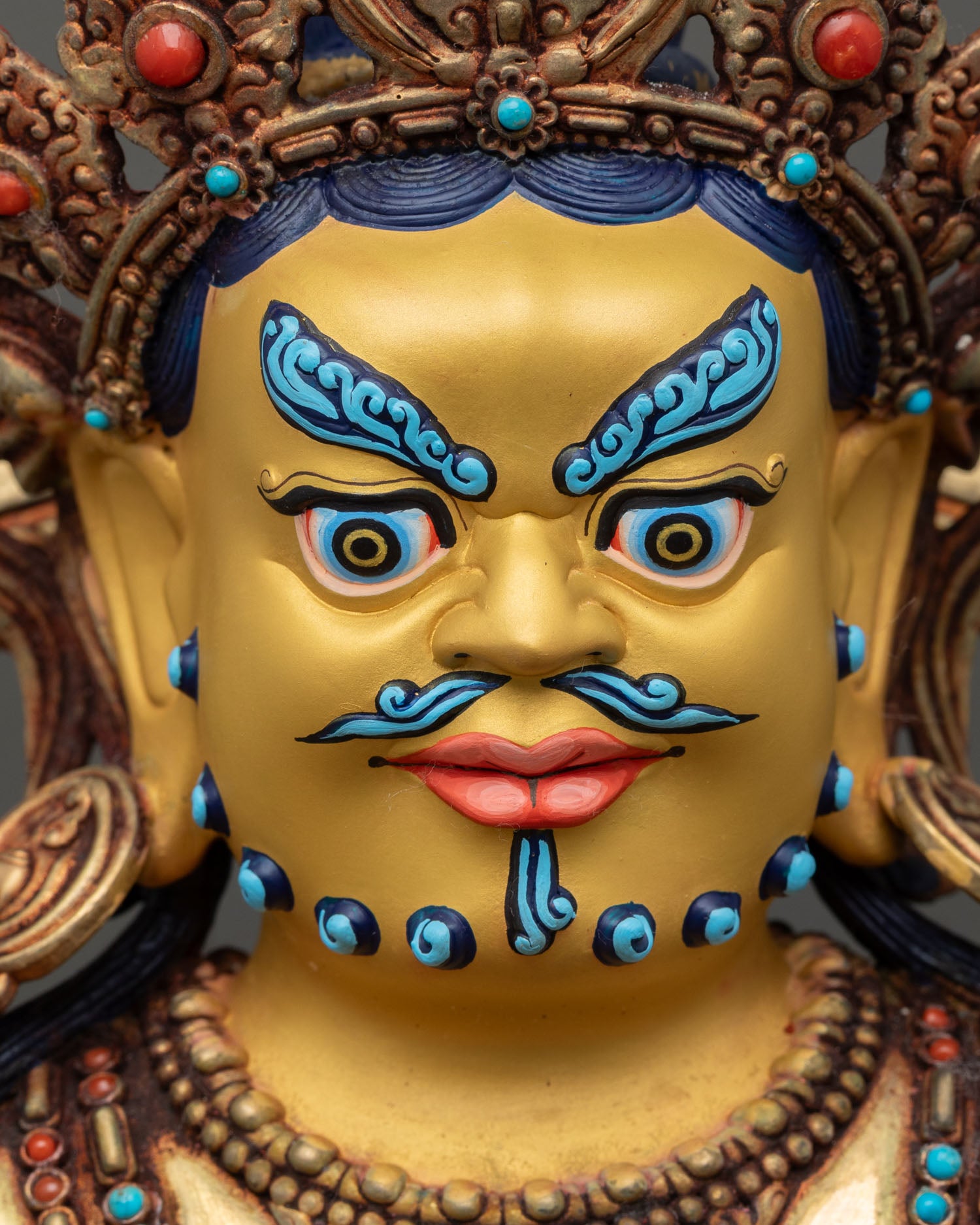 detailed close up dzambhala statue face gold-painted with benevolent expression