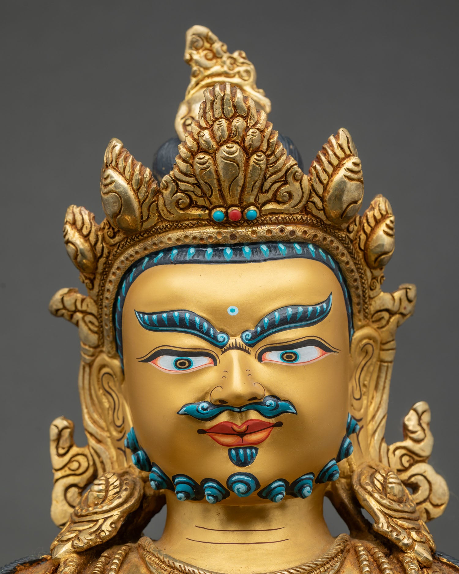 Detailed close-up of Dzambhala statue face, serene expression, gold fire-gilded