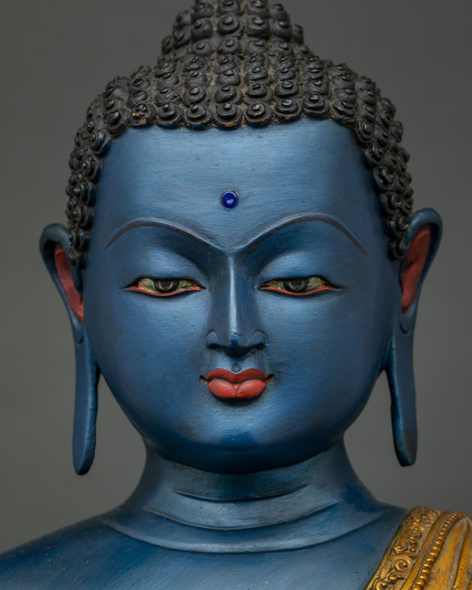 Detailed close up of Akshobhya Buddha statue face with serene expression and blue complexion