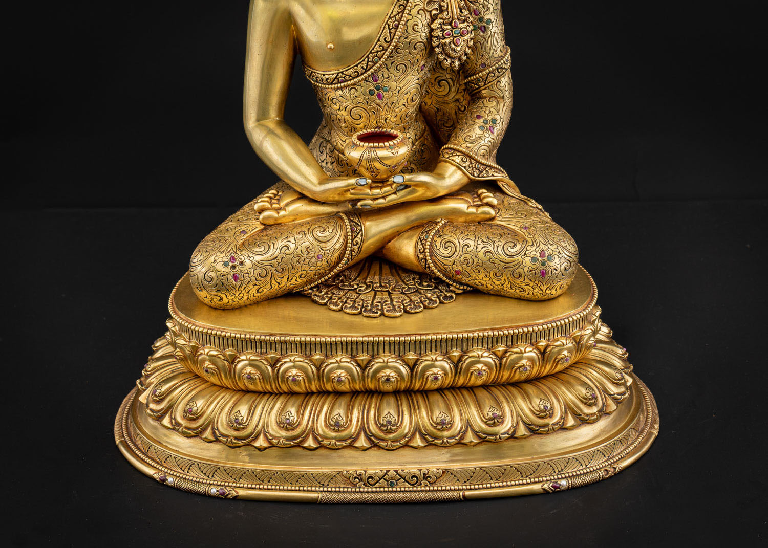 Detailed close‑up of Amitabha Buddha statue pedestal with repoussé carvings and gold gilding