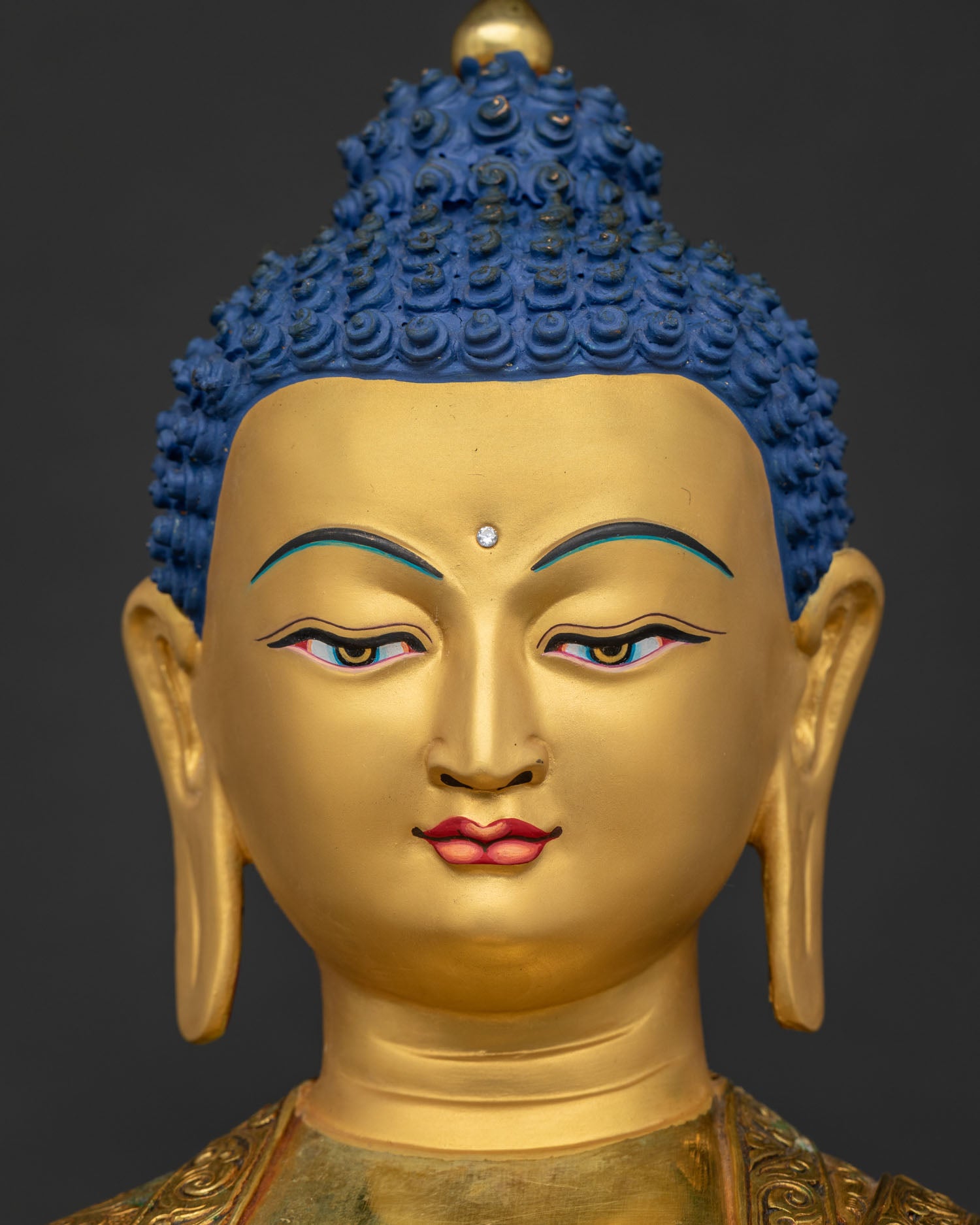 Detailed close up of Amitabha Buddha's serene 24K gold-painted face
