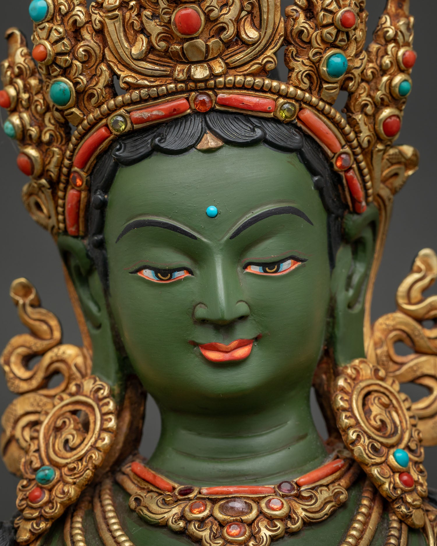 Detailed close up of Green Tara face with hand painted acrylic colors and gold gilded details