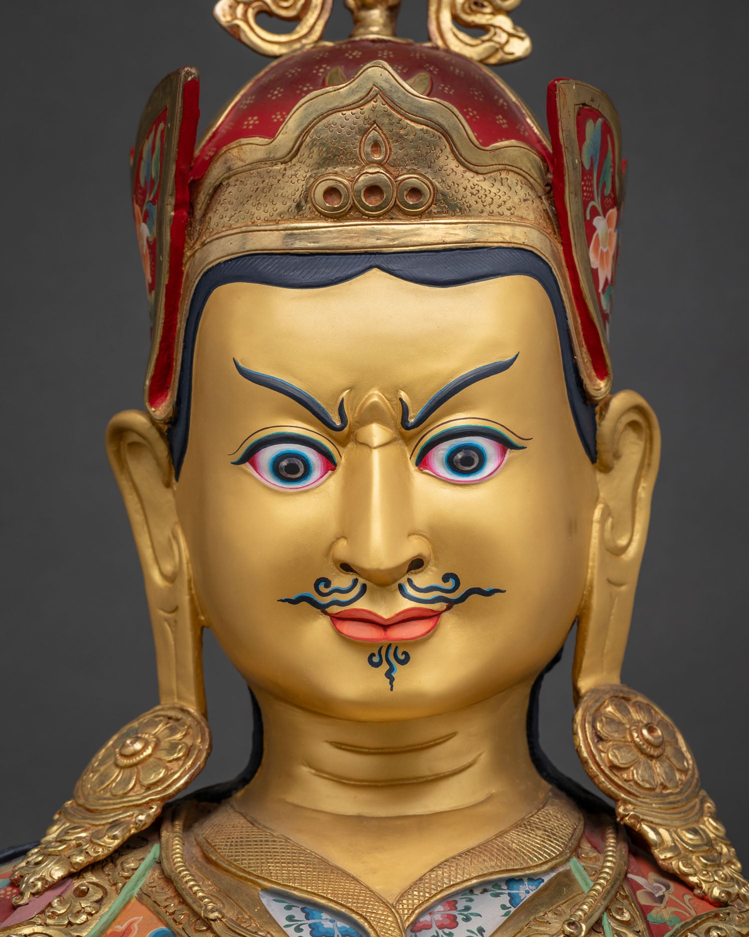 Detailed close up of Guru Rinpoche face with hand-painted features and luminous gold detailing
