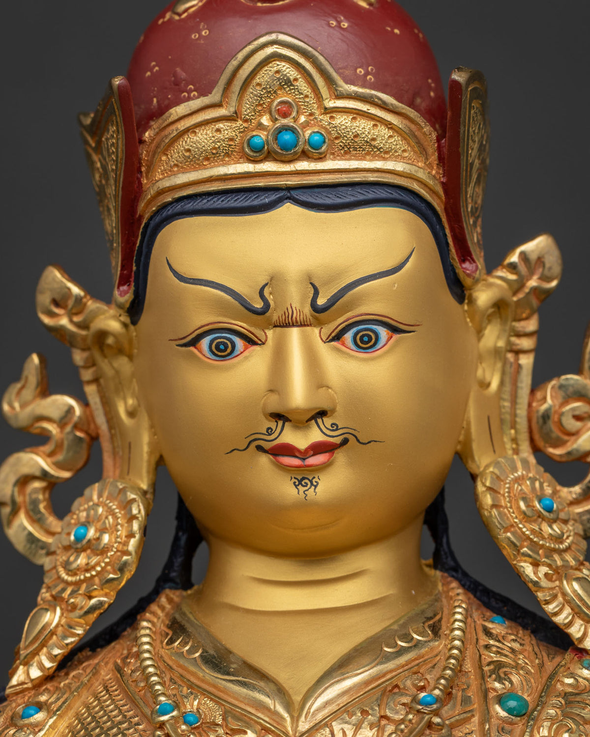 Detailed close up of hand painted gold face on Guru Rinpoche statue