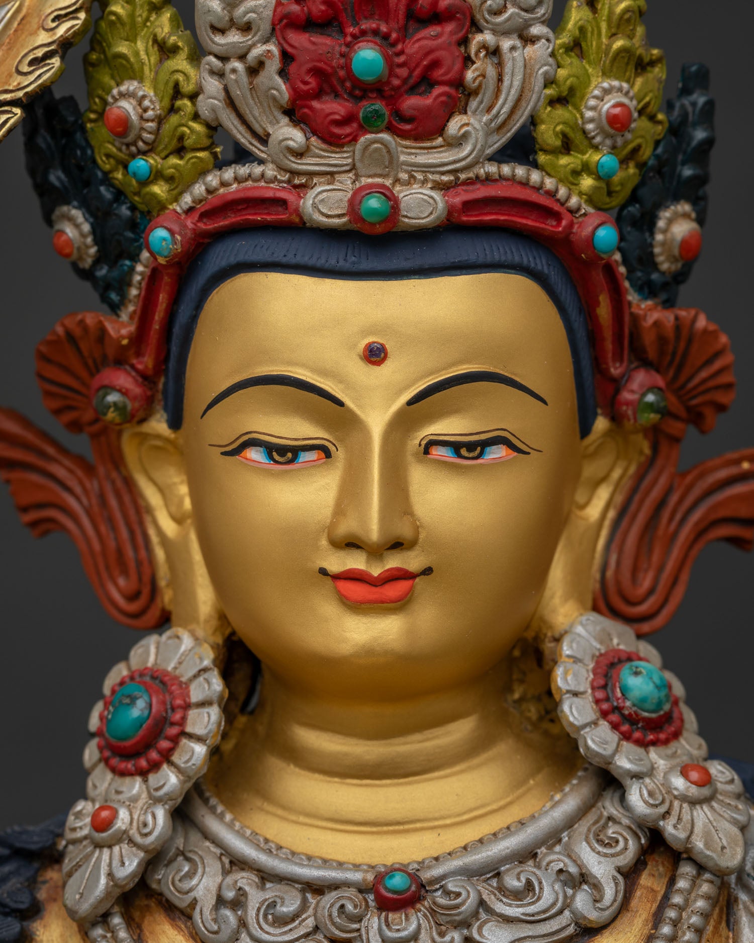 Detailed close-up of Manjushri statue's serene gold-gilded face and jeweled crown