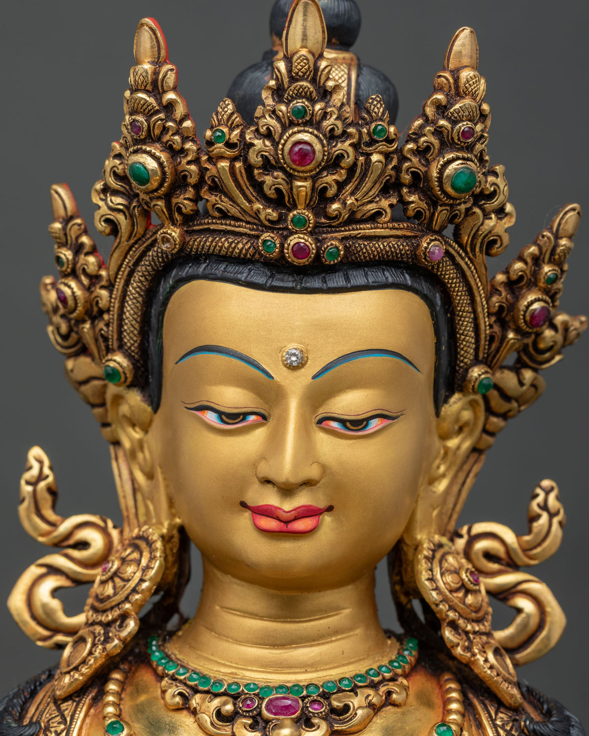 Detailed close up of serene gold-painted face on Vajrasattva statue.