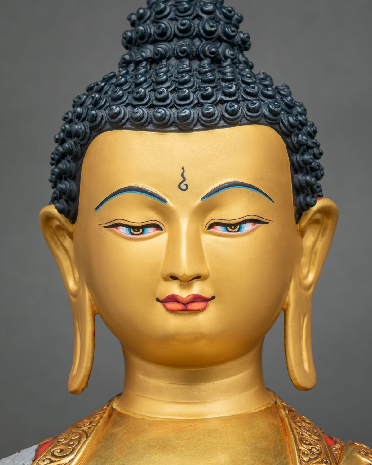 Detailed Close-up of Shakyamuni Buddha statue gold face with deep-blue eyes and hand-painted life story robe