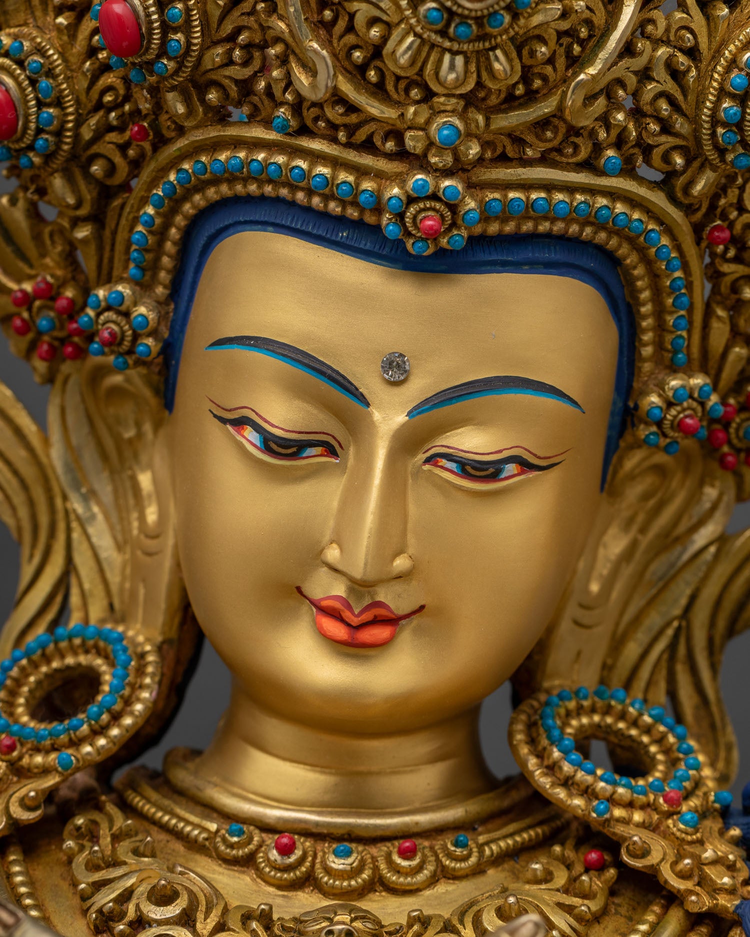 Detailed close-up of Vajradhara statue's gold-painted serene meditative face
