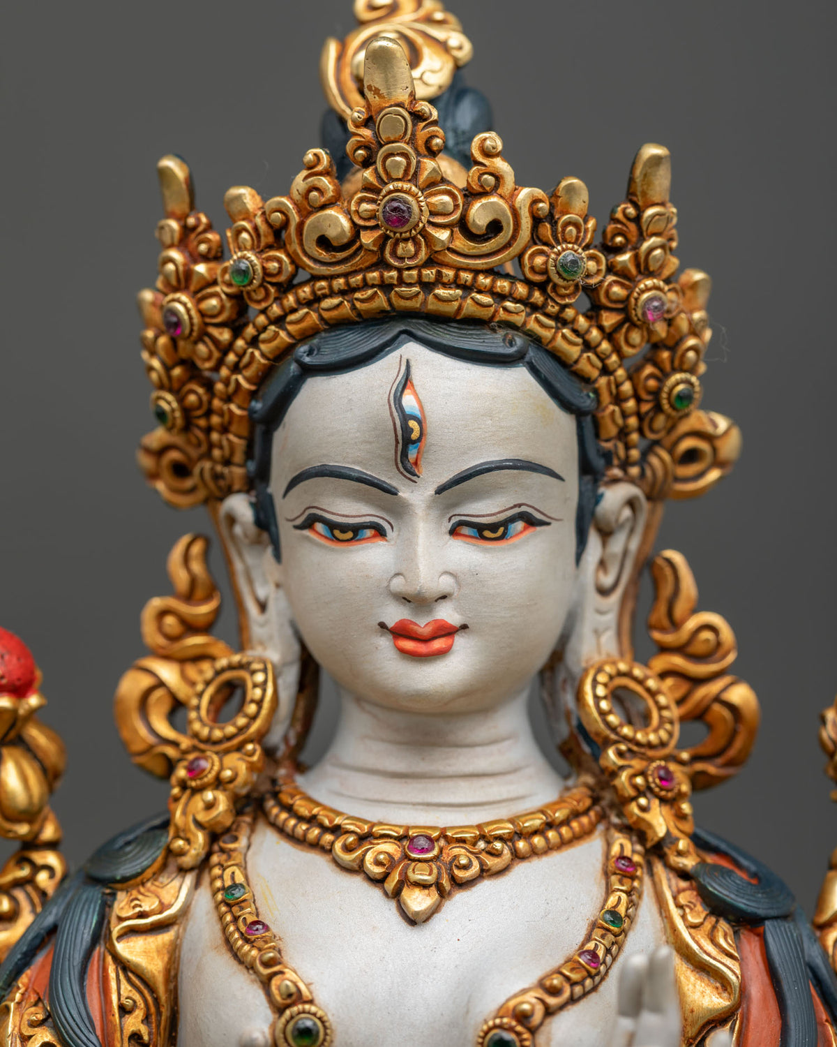 detailed close up of white tara buddha statue face with third eye and five jeweled crown