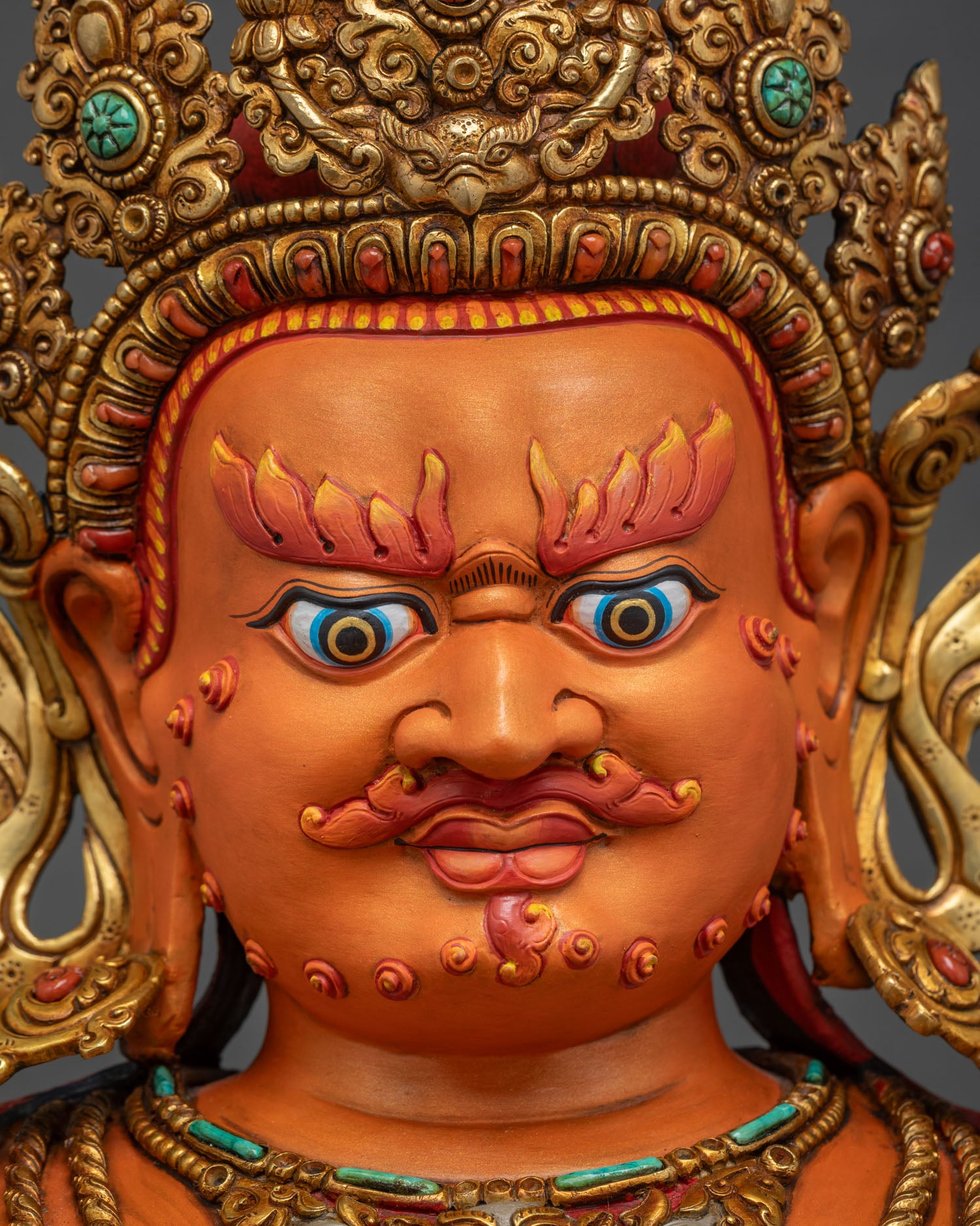Detailed close up of Yellow Dzambhala statue face with wrathful expression and gold crown
