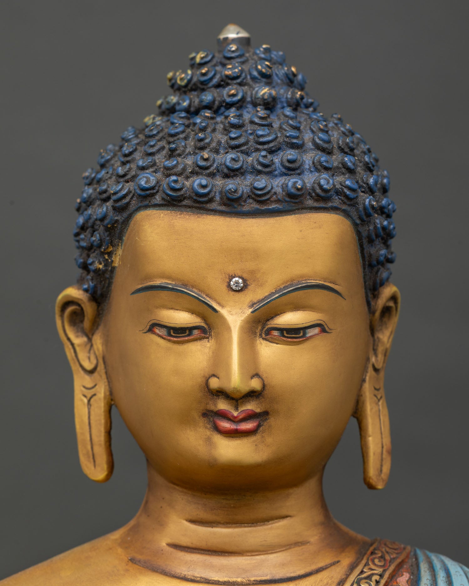Detailed Face Close Up of Lord Shakyamuni Buddha Statue with Serene Gold Painted Expression