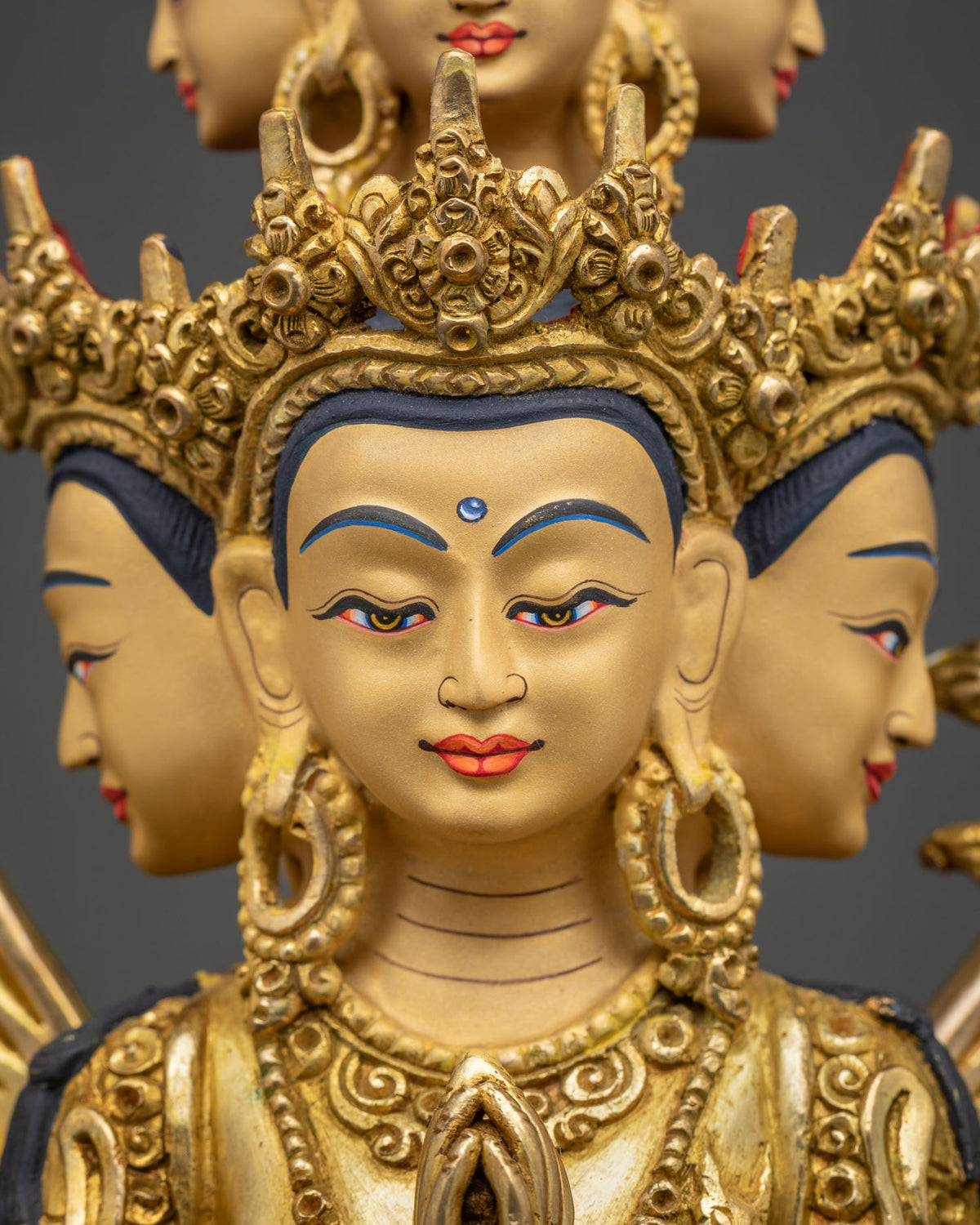 Detailed face close up of Thousand Armed Chenrezig statue with hand-painted eyes and ornate gold crown