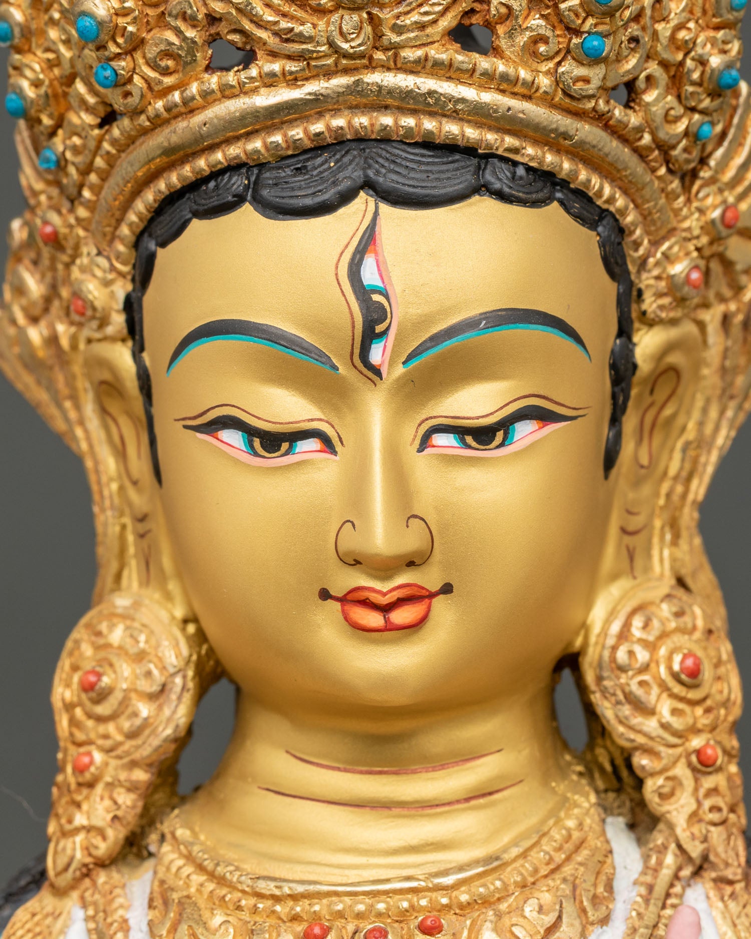detailed face close-up of white tara statue, gold-painted face with seven all-seeing eyes