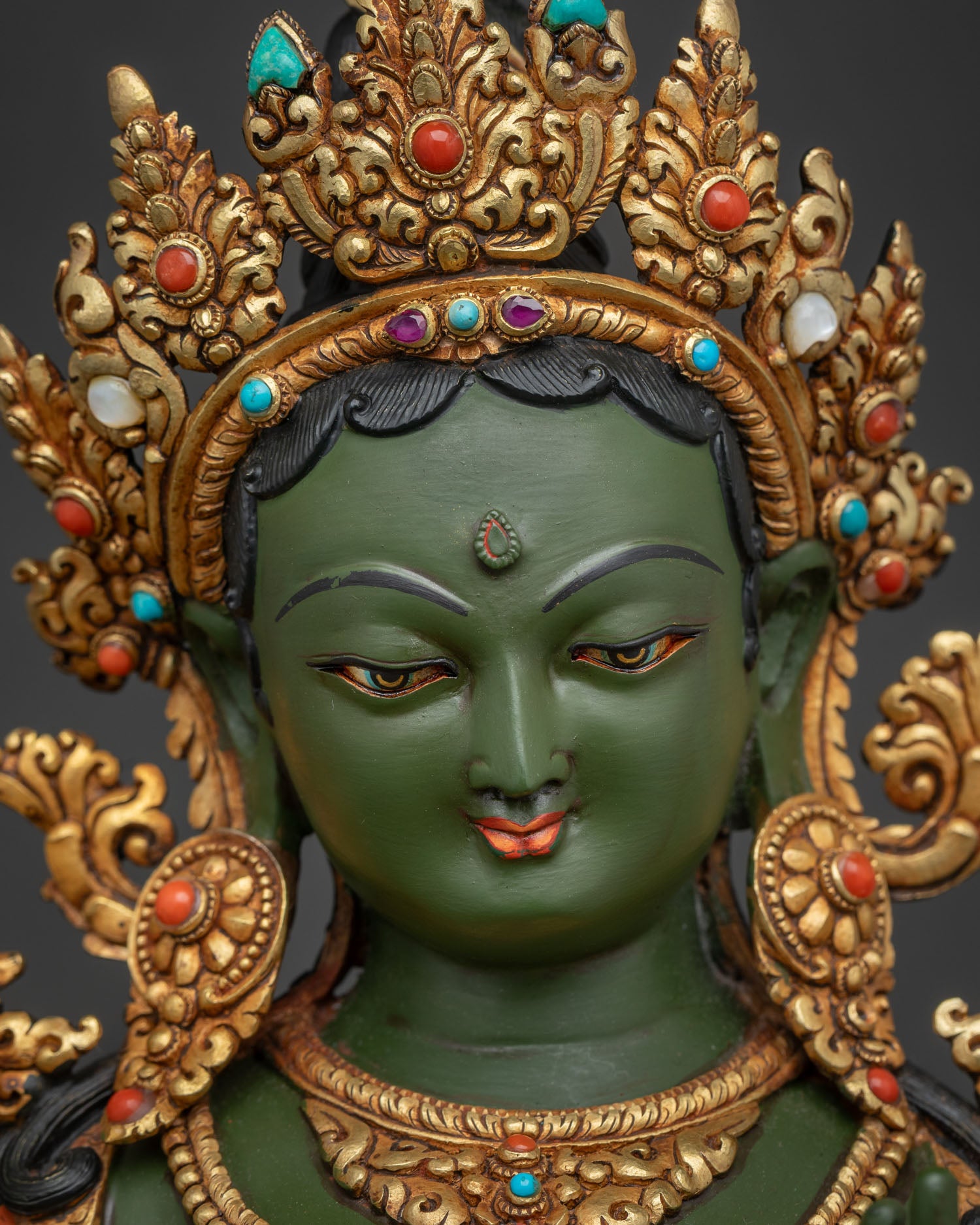 Detailed face close-up showing Five-Jeweled Crown on gold-painted Green Tara statue.