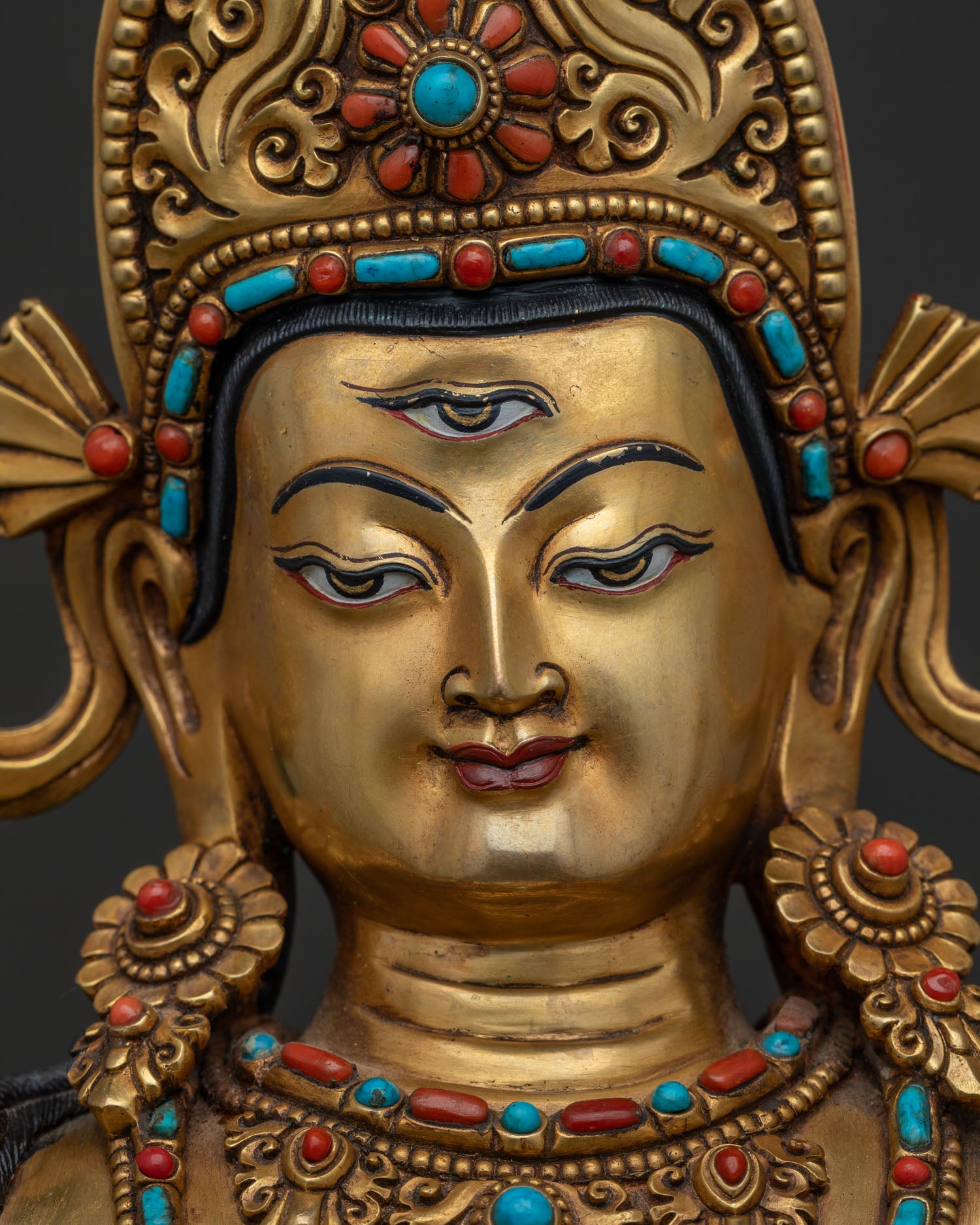Detailed face view of Sakra Indra statue highlighting the third eye and gold craftsmanship