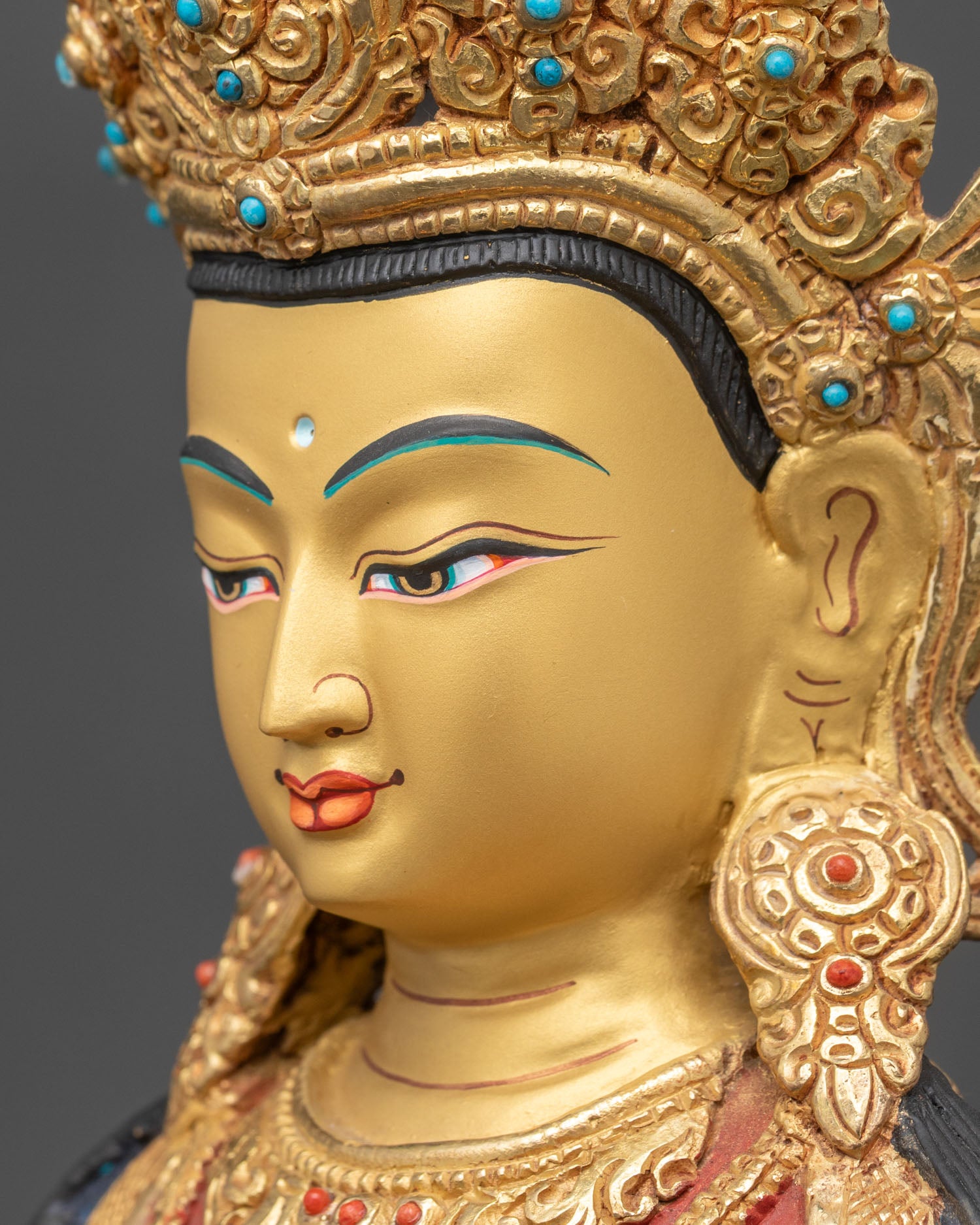 detailed side close up of amitayus statue face showing intricate gold-painted features