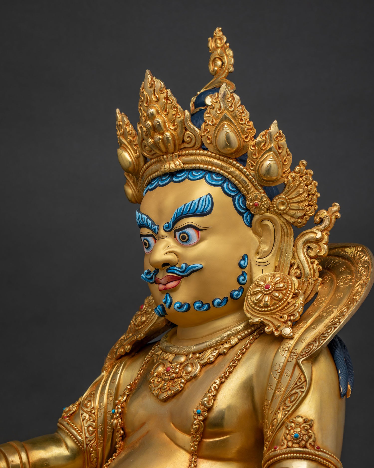 Detailed side close up of Dzambhala statue gold gilded garments and intricate repoussé carving