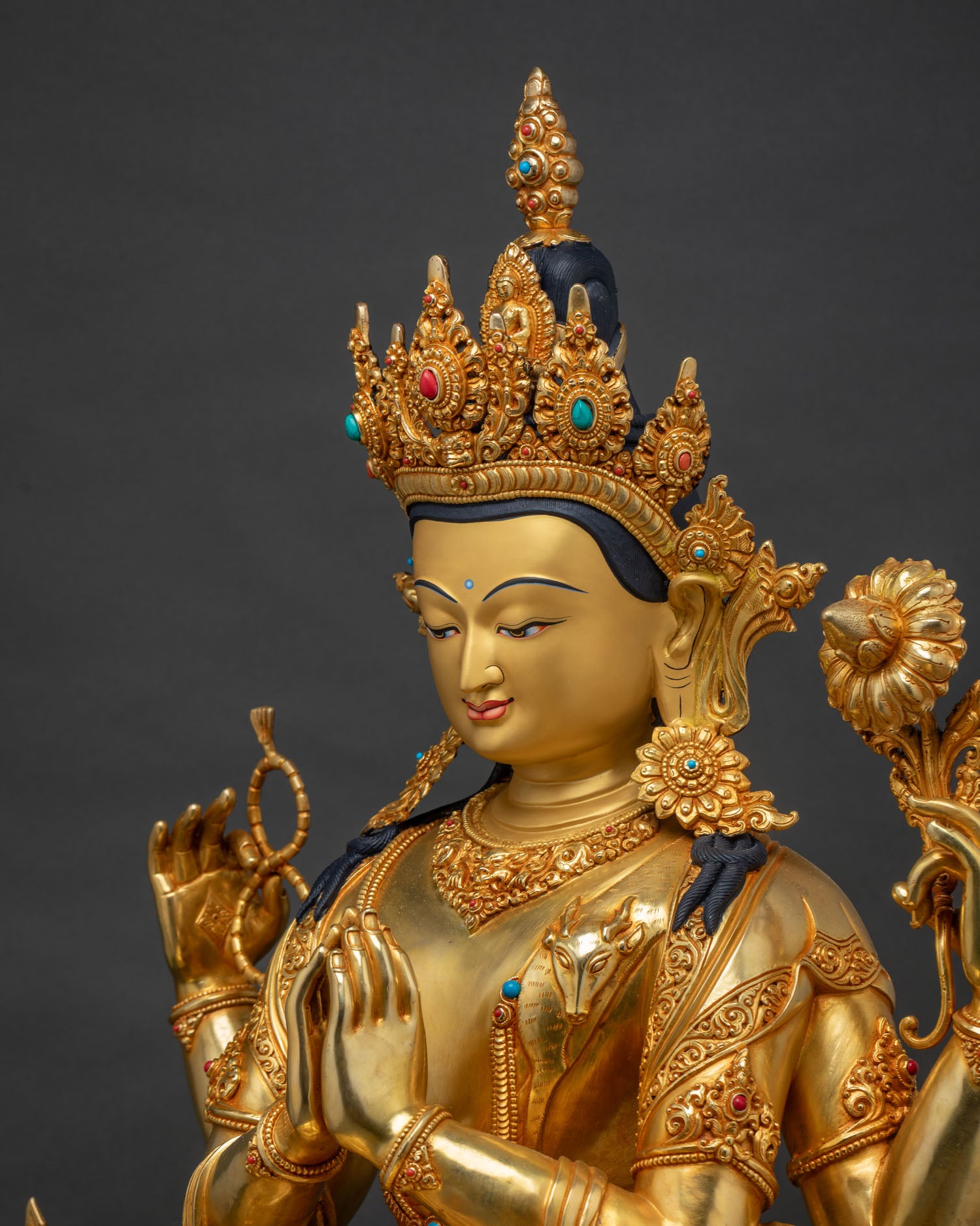 Detailed side close up of four armed Chenrezig statue with hand carved ornaments and gemstones