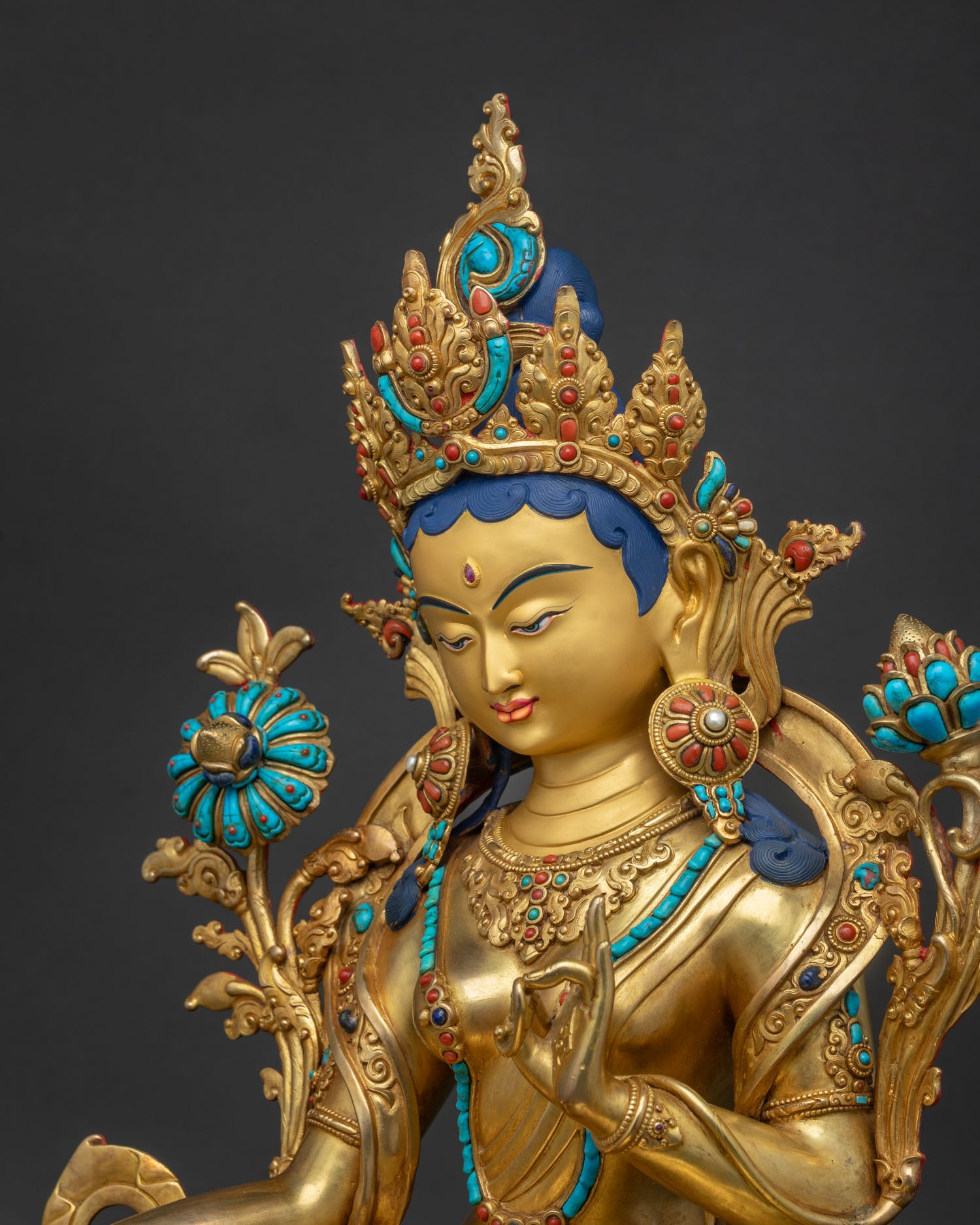 Detailed side close-up of gold-gilded Green Tara statue highlighting the utpala lotus stem.