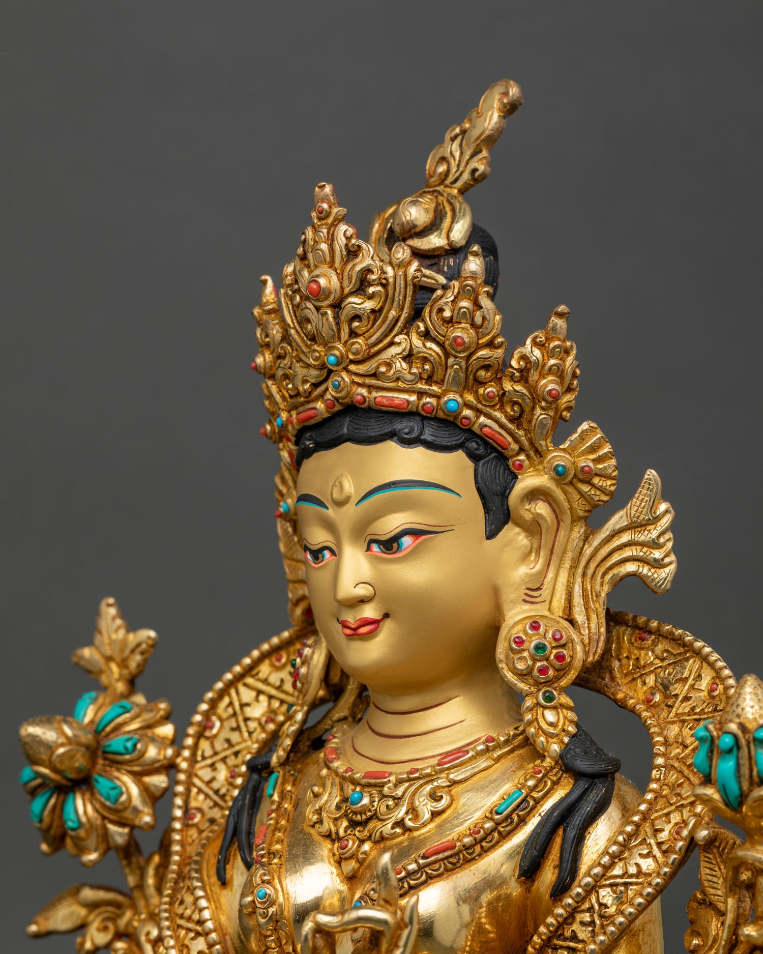 detailed side close-up of green tara statue face, showing turquoise, coral, and lapis inlay