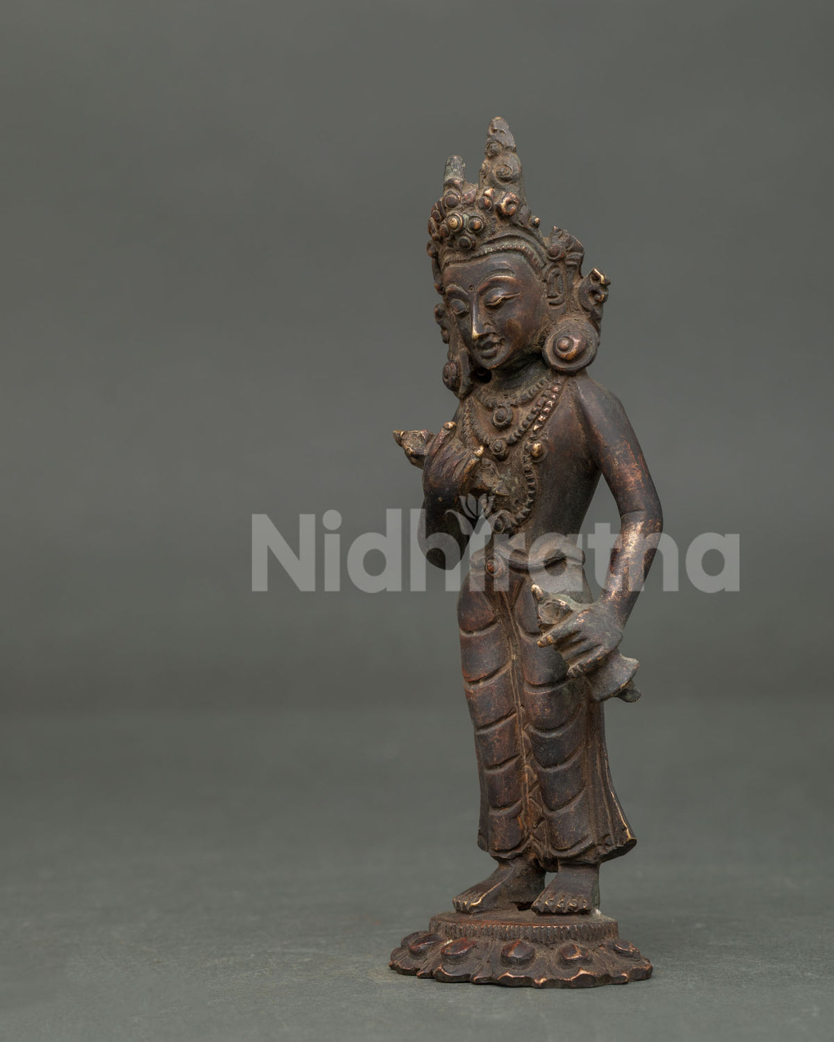 Detailed Side View of Vajrasattva statue with patterned silk garments and lotus pedestal.
