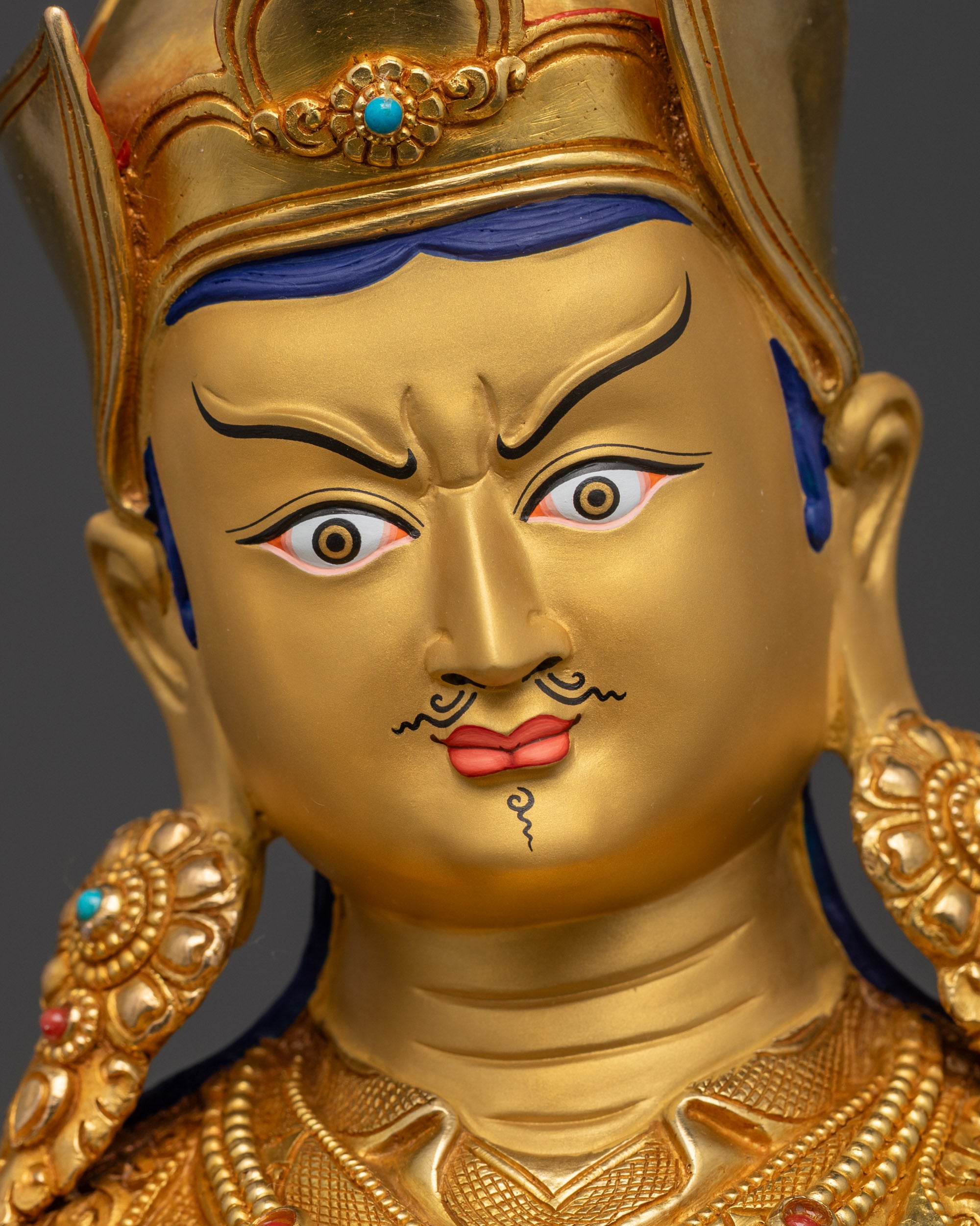 detailed close up face of Guru Padmasambhava gold-gilded features and motif details