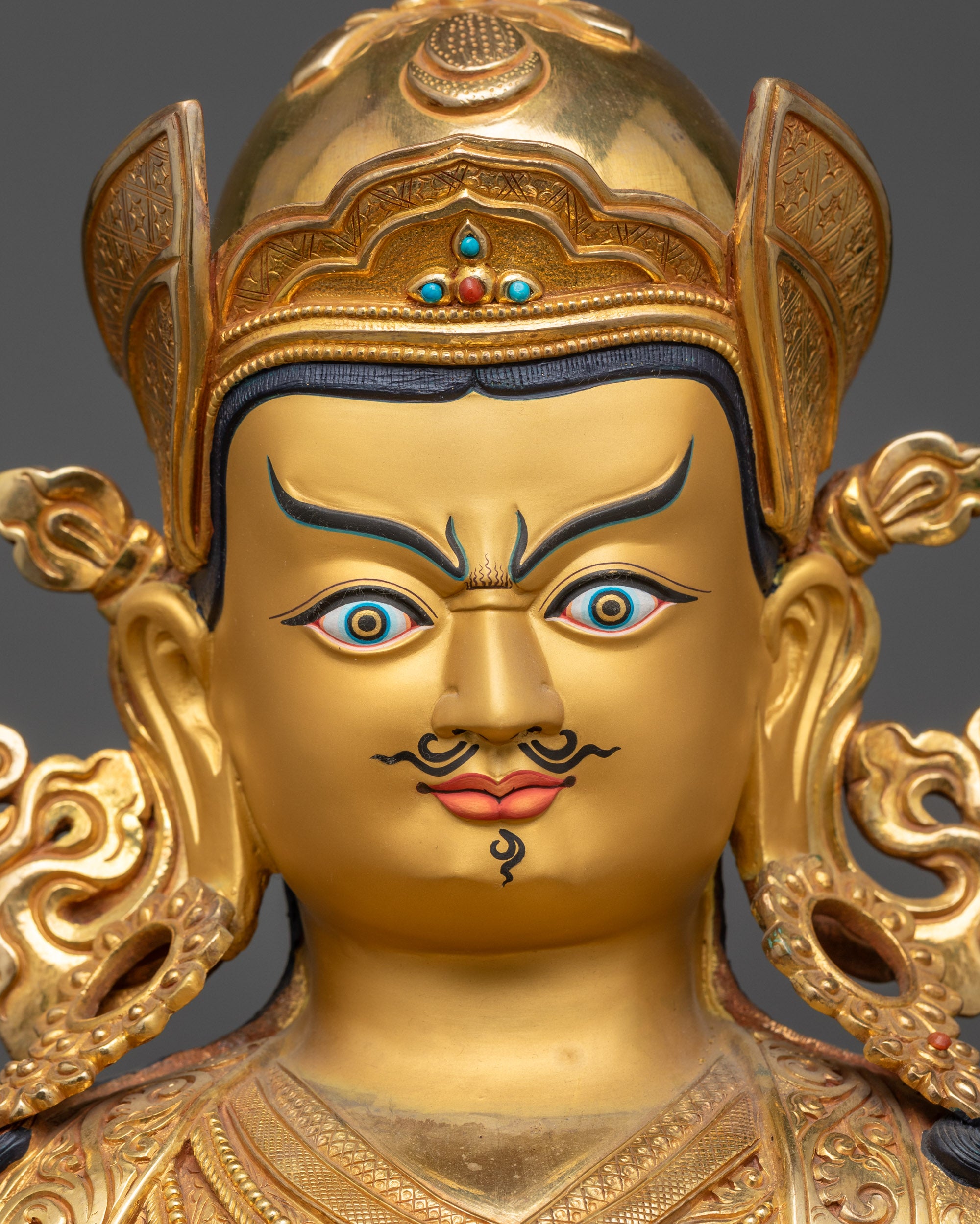 detailed close up face of semi-wrathful gold-gilded Guru Rinpoche statue for altar