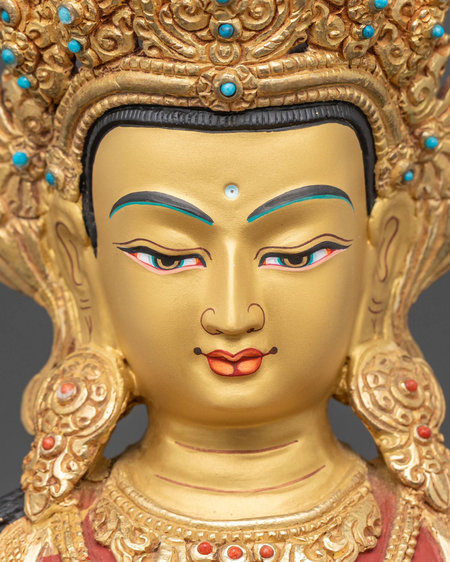 detailed close up of amitayus statue face with gold-gilded jewelry and serene expression