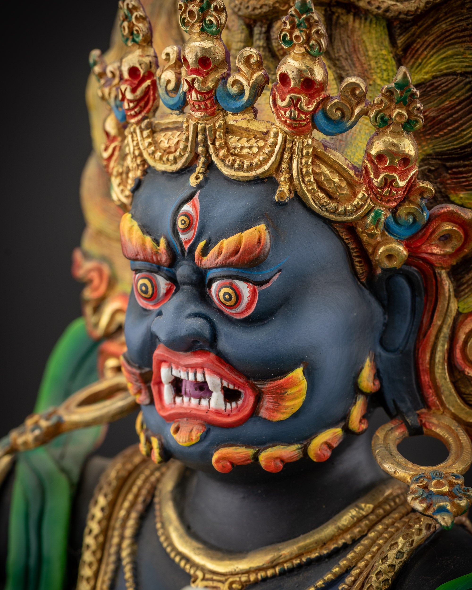detailed side close up of face Vajrapani statue with bared fangs and gold accents