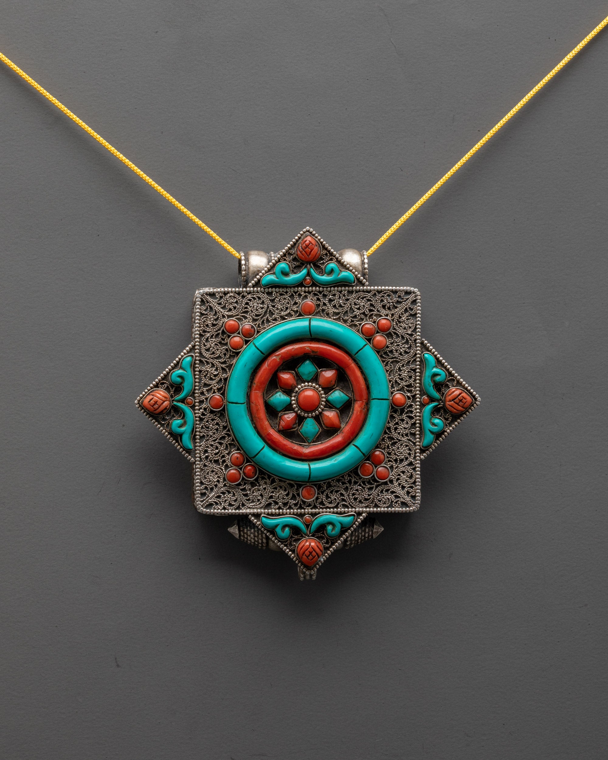 dharma wheel locket front view showing coral, turquoise stones and silver filigree details