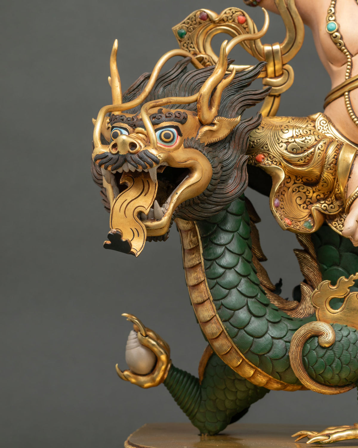 Dragon head detail of White Dzambhala statue with golden horns and a white conch in its claw, Nepal